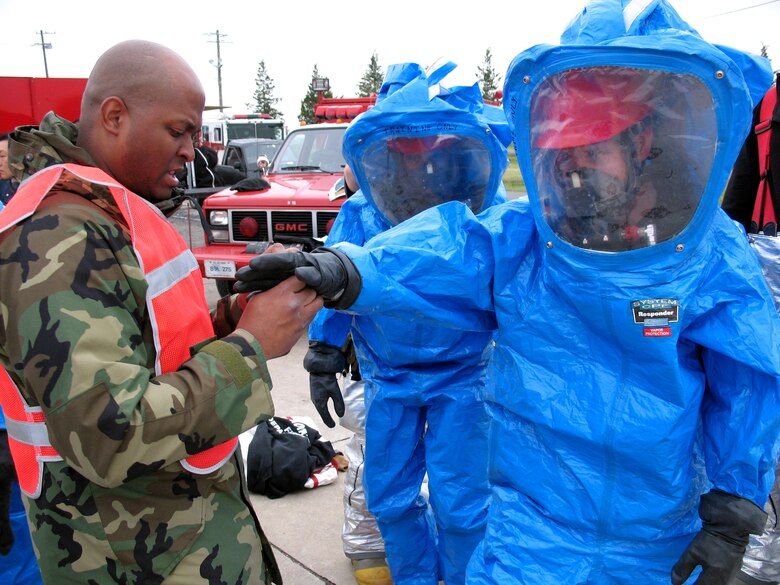 Firefighters help Hazmat entry team members suit up during an in-house exercise April 30 at Yokota Air Base, Japan. The exercise was a refresher for team veterans, but for three of the entry team members it was the final requirement to achieve technician level (U.S. Navy photo/Petty Officer 2nd Class A.C. Rainey)