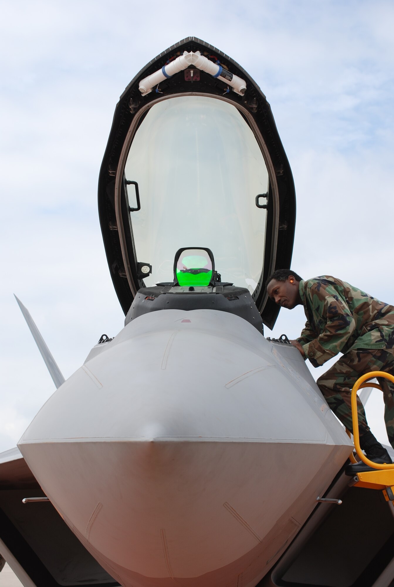 Major Karl D. Lewis, Air Force Reserve's 301st Fighter Wing chief of Public Affairs, takes a rare opportunity to inspect the F-22 Raptor, parked on the wing's ramp alongside the F-16 Falcon, as it makes a brief stopover at NAS JRB Fort Worth, Texas, while flying cross country. (U.S. Air Force Photo/Laura Dermarderosian-Smith)