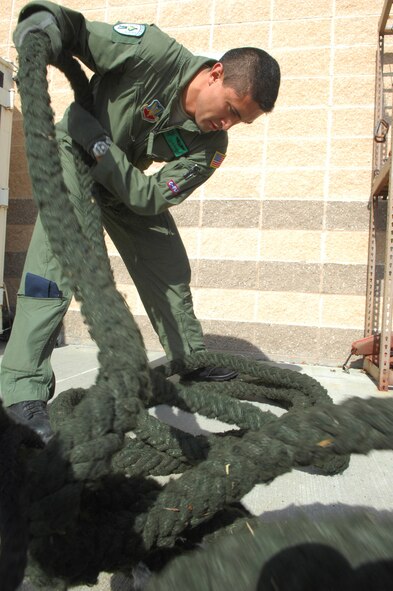 MOODY AIR FORCE BASE, Ga. -- Airman 1st Class Taylor Cifventes, an HH-60G Pave Hawk aerial gunner with the 41st Rescue Squadron at Moody Air Force Base,  inspects and coils a 'fast rope' prior to a training flight here April 25.  Fast ropes are used to rapidly deploy pararescuemen into an area by sliding, much like firemen use a pole.  (U.S. Air Force photo by Senior Airman Angelita Lawrence)