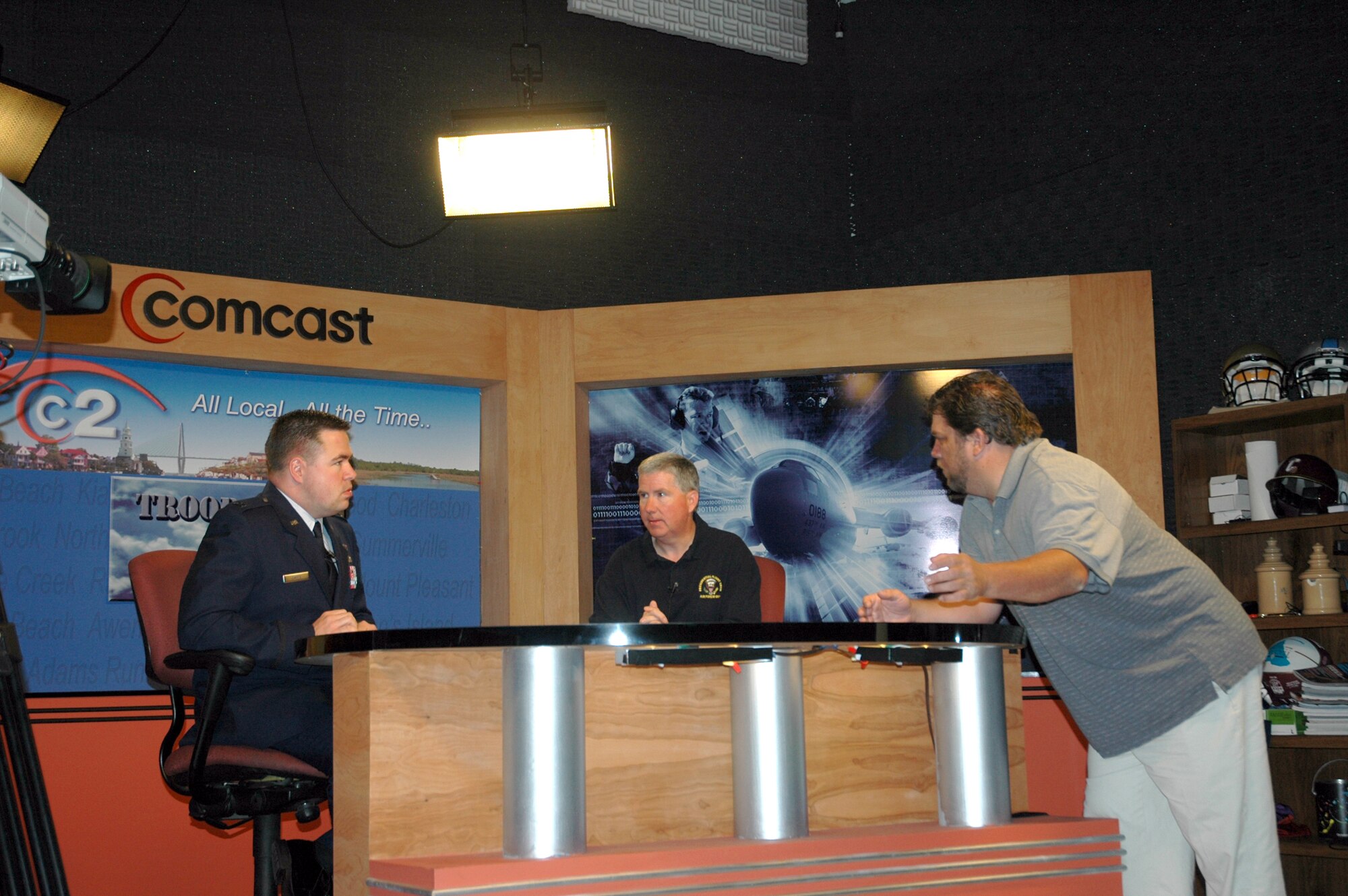 Capt. Wayne Capps (left) and Maj. Bill Walsh (center) of the 315th Airlift Wing Public Affairs, rehearses segments of the wing's new news-talk television program, Troop Talk and talks to the show's director Joe Grammer (right).  (Photo by Tony Clark)