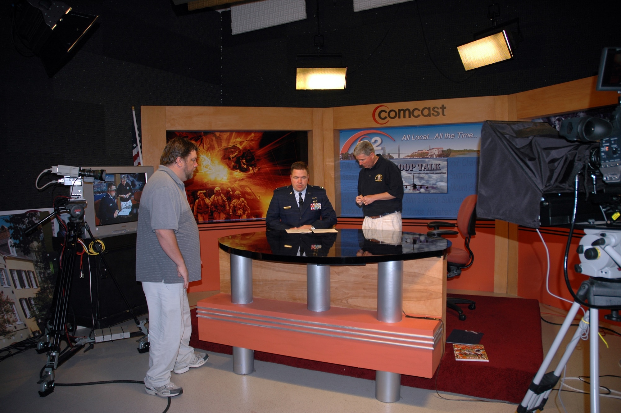 Capt. Wayne Capps (center) and Maj. Bill Walsh (right) of the 315th Airlift Wing Public Affairs, rehearses segments of the wing's new news-talk television program, Troop Talk and talks to the show's director Joe Grammer (left). (Photo by Tony Clark)