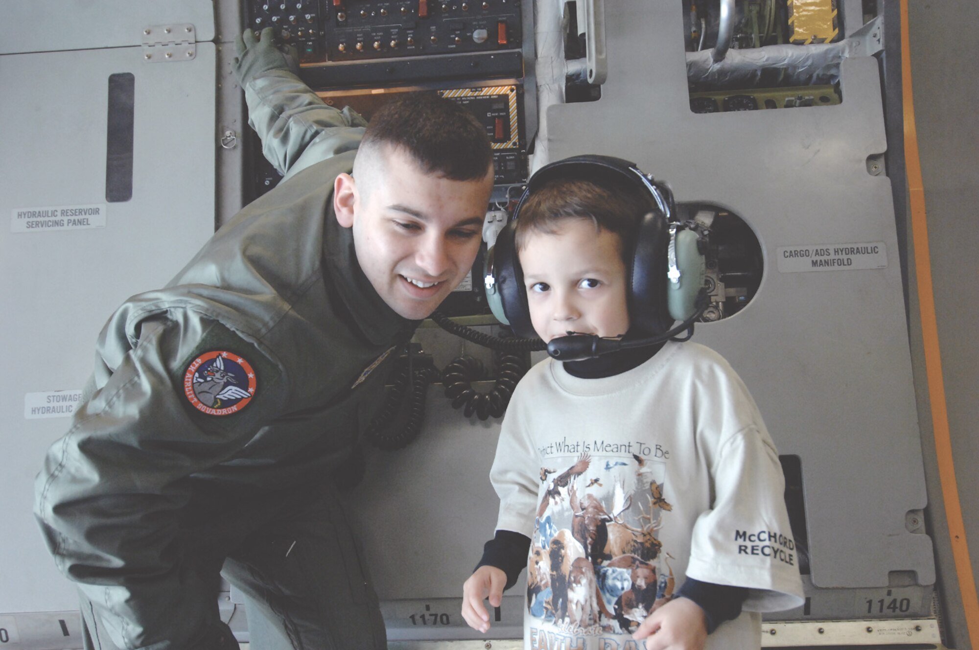 MCCHORD AIR FORCE BASE, Wash. -- Airman 1st Class Timothy Valdez, 4th Airlift Squadron, adjusts the volume on a headset worn by Matthew Shelton April 20 during a tour of a C-17 Globemaster III.  More than 200 children from McChord's child development center and Escape Zone toured the aircraft as part of Month of the Military Child, a month designated to applaud military children for the sacrifices they make on a daily basis. (U. S Air Force Photo by Abner Guzman)