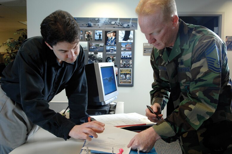 MCCHORD AIR FORCE BASE, Wash. -- Base multimedia manager Randy White, 62nd Communications Squadron, left, accepts a work order for retirement certificates from Master Sgt. John Matthews, 62nd Airlift Wing inspector general's office, April 24, 2007 in Bldg.100. (U.S. Air Force Photo By Abner Guzman)