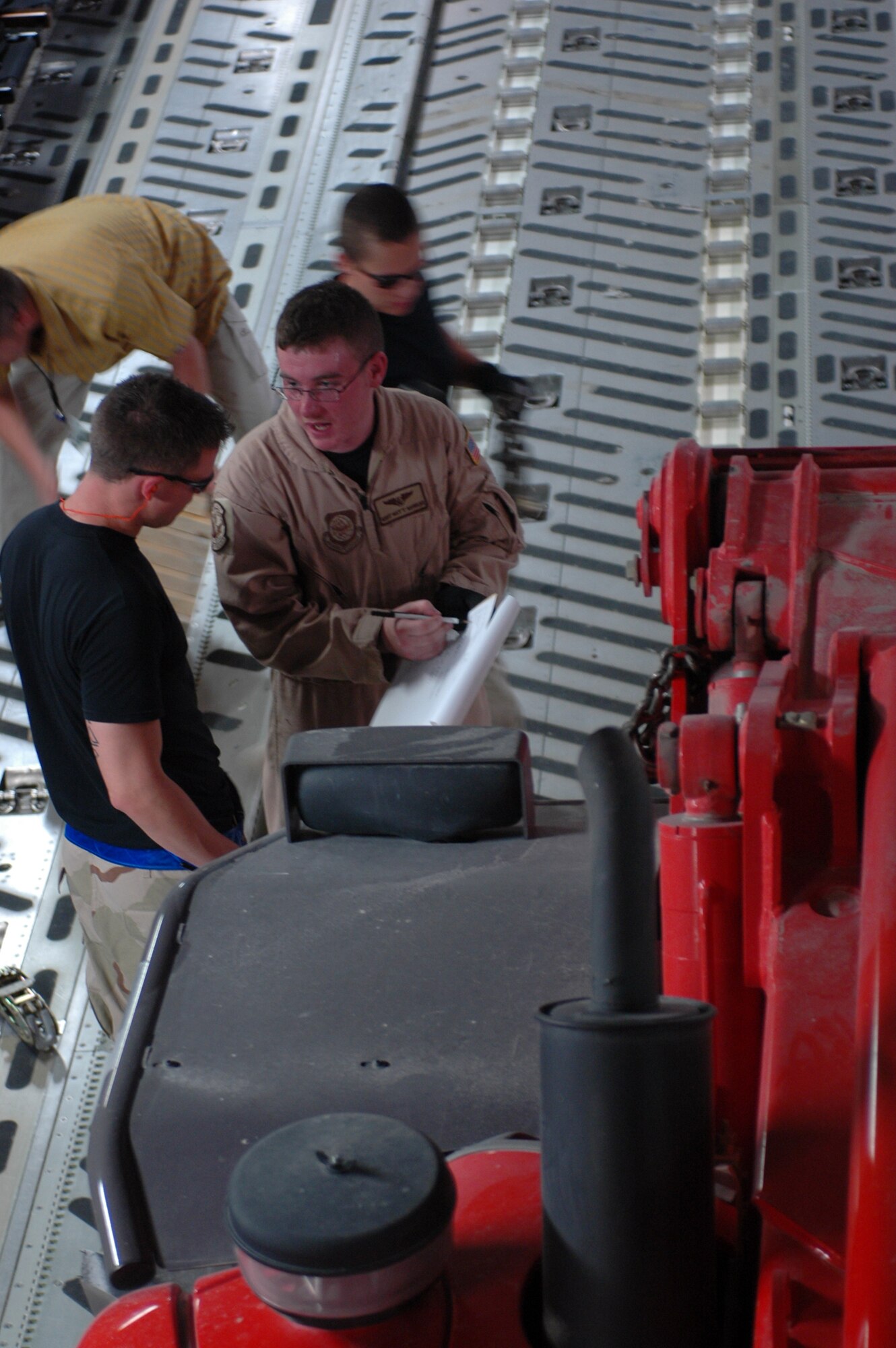 Staff Sgt. Matt Shields, 816th Expeditionary Airlift Squadron loadmaster (center), works with 8th Expeditionary Air Mobility Squadron personnel to configure the floorplan on a C-17 Globemaster for a mission April 25. (U.S. Air Force photo/Senior Airman Erik Hofmeyer)