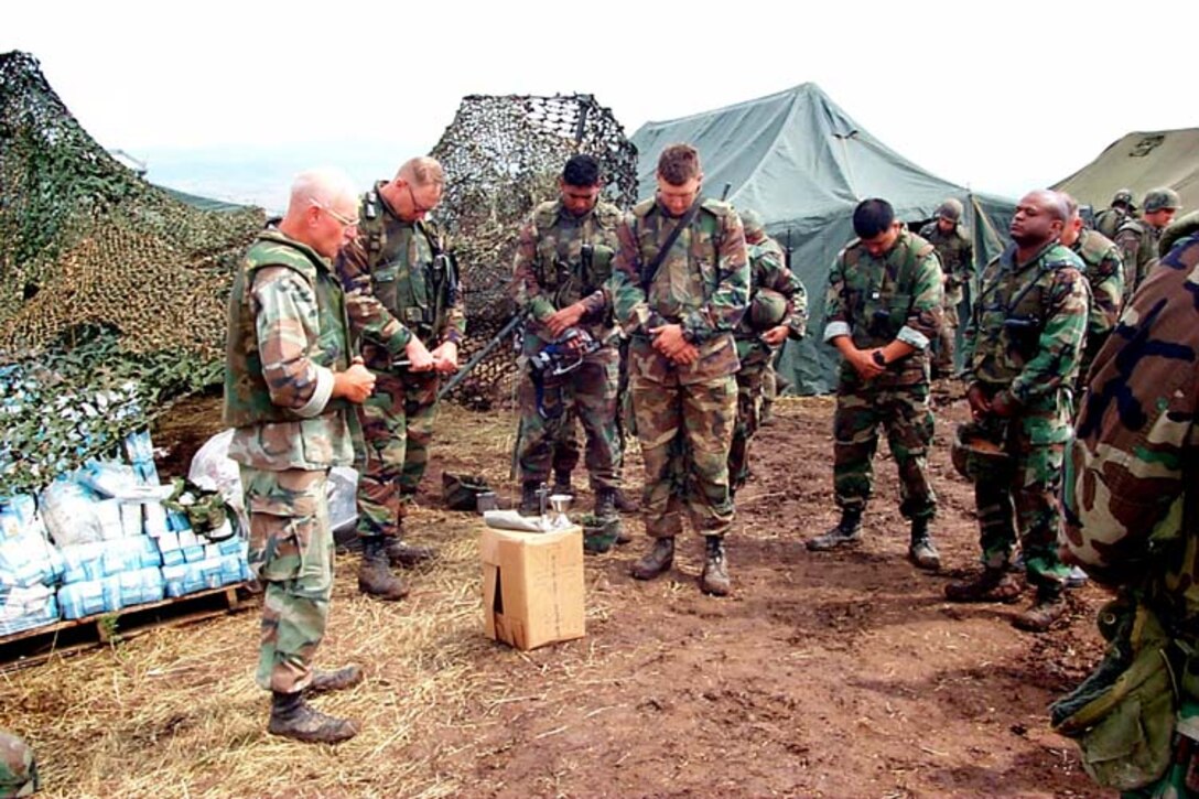 Navy Chaplain Cmdr. Patrick Hahn (left) leads a field prayer service at the 26th Marine Expeditionary Unit forward operating base near Cernica, Kosovo, June 20. Elements of the 26th deployed from ships of the USS Kearsarge Amphibious Ready Group as an enabling force for KFOR in support of the peacekeeping mission Operation Joint Guardian. Chief Warrant Officer Seth Rossman, USN