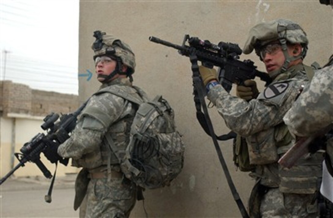 U.S. Army Pvt. Joseph Burton (left) and Staff Sgt. John Martinez clear a street corner during a raid in the Tamooz neighborhood of Mosul, Iraq, on April 27, 2007.  Burton and Martinez are attached to the 3rd platoon, Delta Company, 2nd Battalion, 7th Cavalry Regiment, 4th Brigade Combat Team, 1st Cavalry Division.  