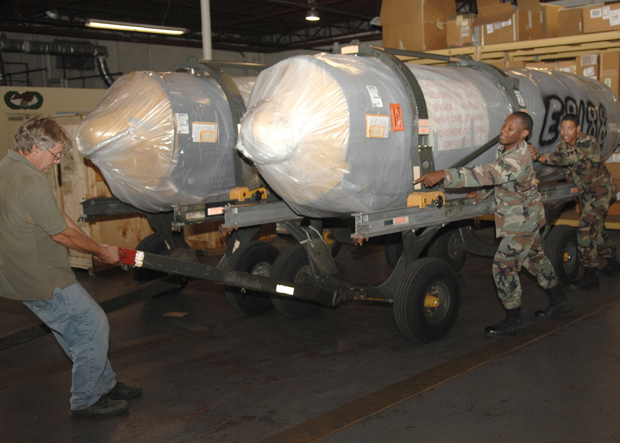 Ken Seronick, SrA James Dixson and SrA Manuel McEllroy, 4th Logistics Readiness Squadron, Seymour Johnson AFB, Goldsboro, North Carolina move a F-15 engine in order for it to be loaded onto the back of a flatbed truck to be transported on 1 August 2007.
(U.S. Air Force photo by Senior Airman Jessica Klingler)