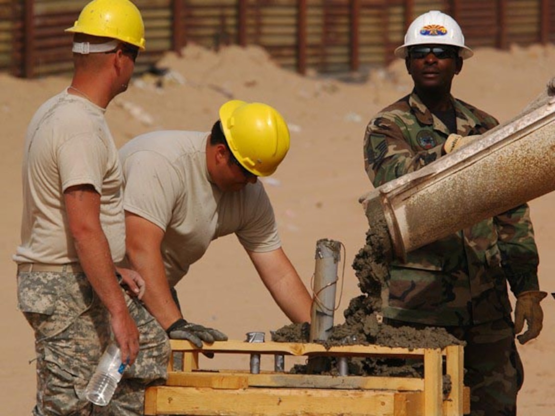 Master Sgt. Darryl S. Ennels, of the 175th Civil Engineer Squadron, in the green battle dress uniform, directs concrete pouring into forms used to create bases for light poles which are positioned between the primary and secondary fences along the Arizona-Mexico border, June 6, 2007.  Two members of the North Dakota Army National Guard 188th Engineer Company are troweling the concrete as it fills the form.  The joint force mission of Task Force Diamondback, under Operation JUMP START, is to erect and reinforce segments of border fence and to construct obstacles along the border to help secure the southwest U.S.-Mexico border.  (USAF photo/Senior Master Sgt. David H. Lipp)
