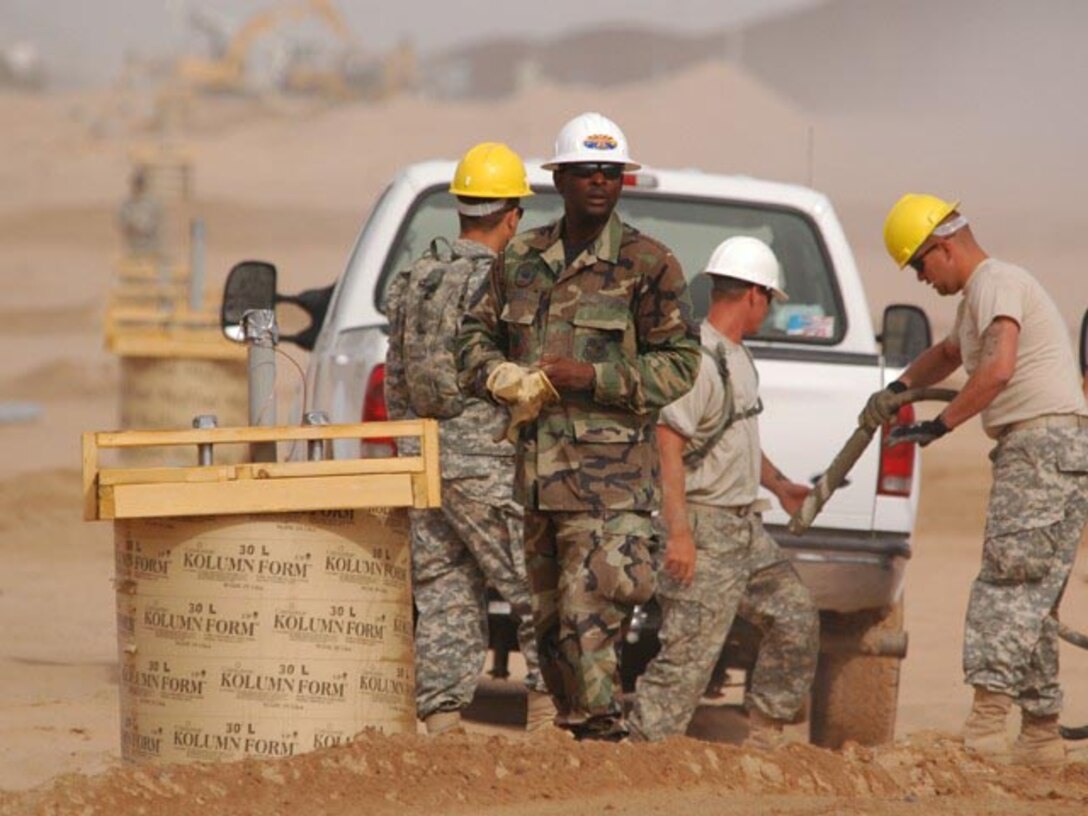 Master Sgt. Darryl S. Ennels, of the 175th Civil Engineer Squadron, in the green battle dress uniform, directs concrete pouring into forms used to create bases for light poles which are positioned between the primary and secondary fences along the Arizona-Mexico border, June 6, 2007.  (USAF photo/Senior Master Sgt. David H. Lipp)
