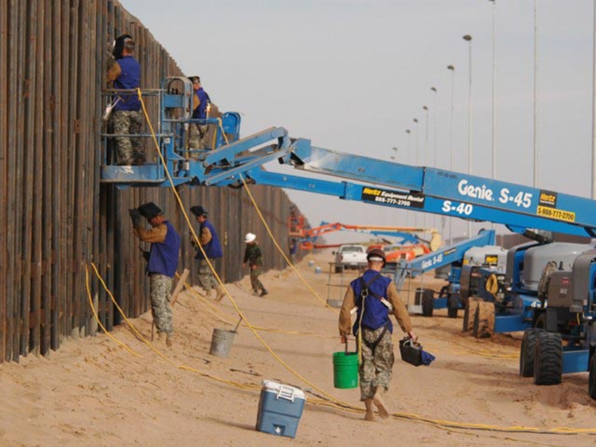 Task Force Diamondback U. S. Army soldiers from the 188th Engineer Company apply welding to the U.S. side of the primary steel border fence at the U.S.-Mexico border June 6, 2007.   The soldiers, from the North Dakota Army National Guard, are using motorized boom lifts which allow them to safely work at various heights along the fence.  The mission of Task Force Diamondback, under Operation JUMP START, is to erect and reinforce segments of border fence and to construct obstacles along the border to help secure the southwest U.S.-Mexico border.  (USAF photo/Senior Master Sgt. David H. Lipp)
