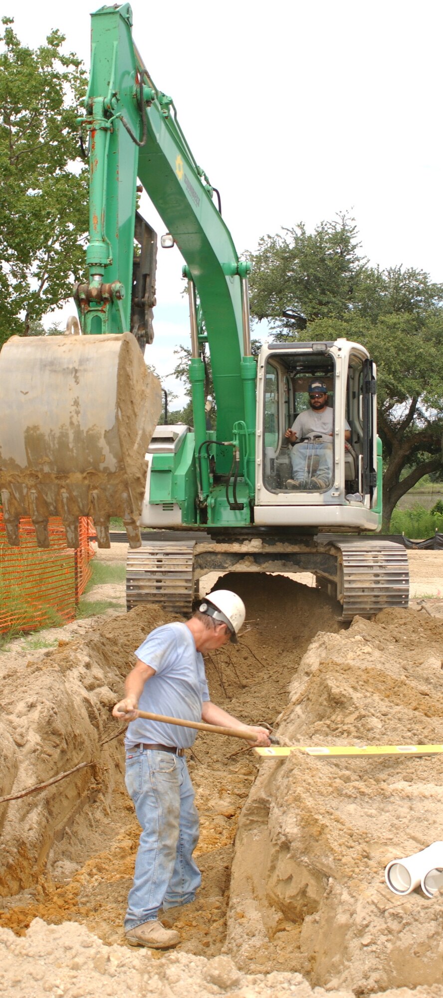 Trackhoe operator Stephen Arnold and his father, Cecil, prepare trenches for water and sewer lines July 20 at the former Harrison Court base housing area.  They work for JESCO, Inc. of Tupelo, a subcontractor for Hunt-Yates.  The fenced site is being prepared as a “man camp” with approximately 60 trailer spaces for contractor use while Keesler’s military family housing project, the largest in Air Force history, takes place.  No decision has been made for the use of Harrison Court after the housing project is completed, according to Craig Merkerson of the 81st Civil Engineer Squadron’s program management office.  (U.S. Air Force photo by Kemberly Groue)