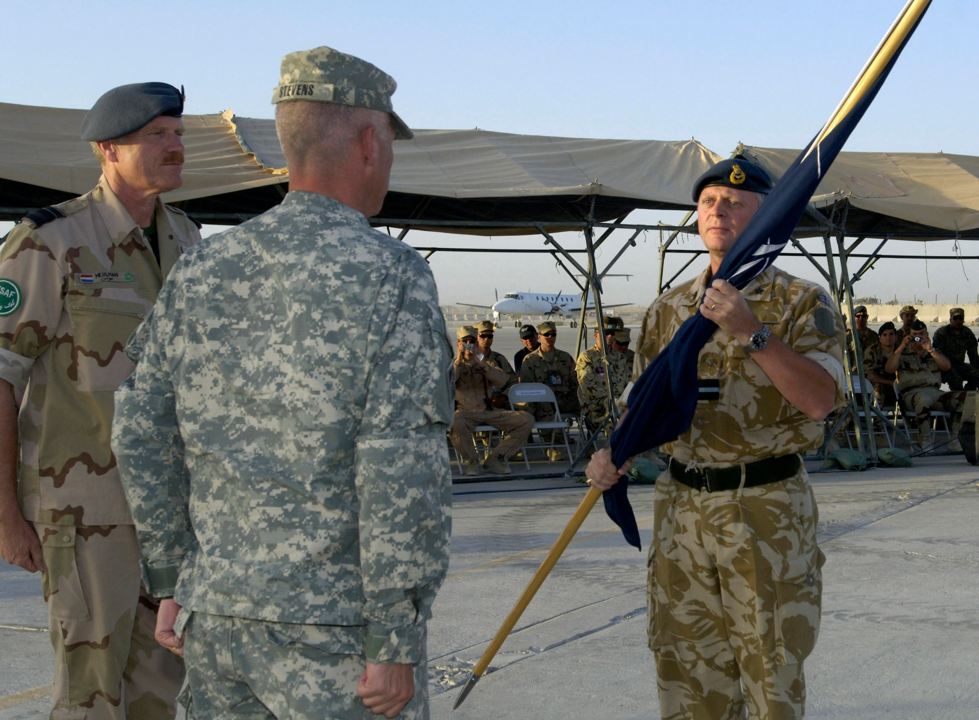 Royal Air Force Air Commodore Ashley Stevenson (right) takes command of Kandahar Air Field, Afghanistan, from U.S. Army Col. Richard L. Stevens July 31. Presiding over the historic change-of-command ceremony is Royal Netherlands Maj. Gen. Freek Meulman (left), the International Security Assistance Force deputy commander for air.   The ceremony culminated a year-long effort to bring Kandahar under NATO control.  The ceremony marked the first time NATO has taken full control of a large airfield and operational staging base in an active operational theater using a multi-national team. (U.S. Air Force photo/Master Sgt. Jim Varhegyi)