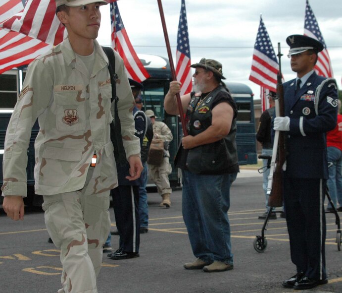 Ellsworth's Airmen return home July 27 and are flanked by Staff Sgt. Rueben TrejoSanchez, NCOIC of Ellsworth's honor guard and Patriot Guard Rider Jay Wilson. The integrated honor guard to welcome the Airmen home was comprised of rifles and flags, which formed a corridor of honor and respect for the Airmen to walk through to in-process Ellsworth. (U.S. Air Force photo by Maj. Karen Roganov)