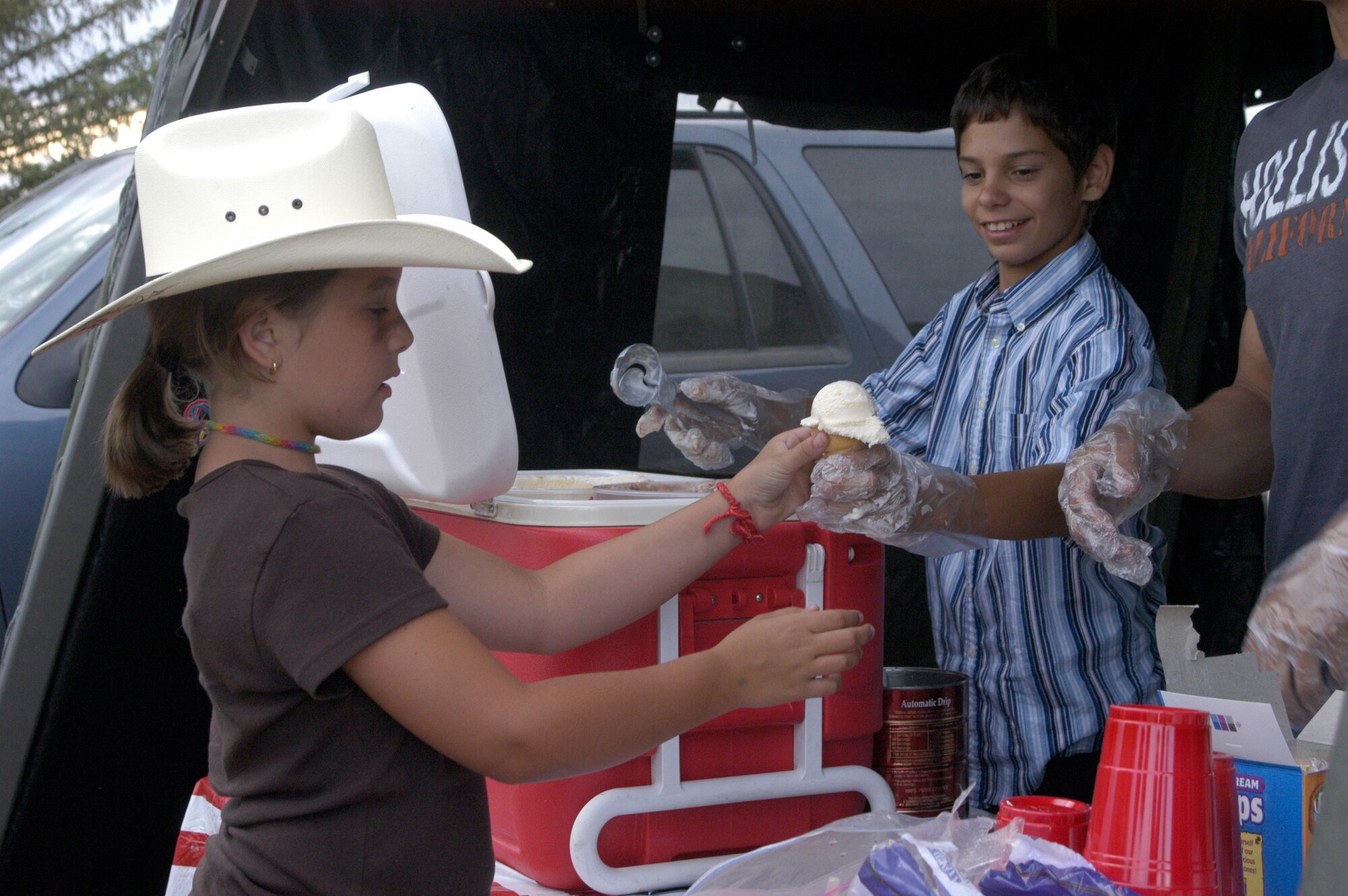 Kyle Johnson, son of a service member, serves Savannah Youngblood, a visitor from Texas, a scoop of vanilla ice cream during the ice cream social and dance here July 21 during Fort D.A. Russell Days. Local and base families attended the event, which also included an instructor teaching western dance (Photo by 2nd Lt. Lisa Meiman).
