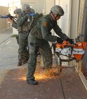 MINOT AIR FORCE BASE, N.D. -- Staff Sgt. Eric Argentieri, 91st Security Forces Group Tactical Response Force Flight, cuts a fence apart with a saw before entering to perform a building sweep with his team during an exercise held at POD 4 here July 31. The TRF’s goal is to deny access to strategic weapons and strategic weapon facilities. (U.S. Air Force photo by Senior Airman Christopher Boitz)