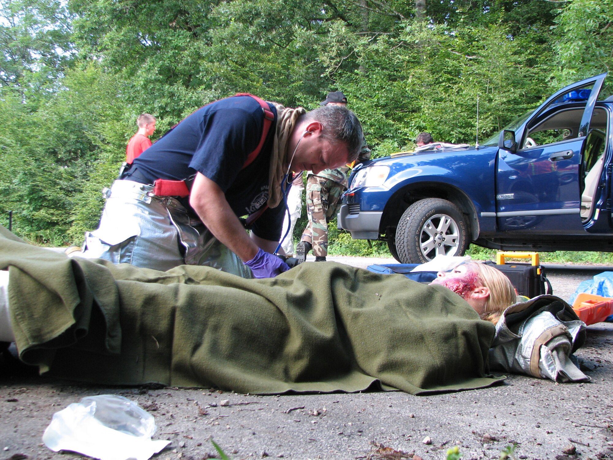 SPANGDAHLEM AIR BASE, Germany – Harry Heidgen, 52nd Civil Engineer Squadron firefighter, treats Airman Basic Lindsey Keene, 52nd Services Squadron, who played an injured Airman during a simulated C-17 crash at Oberweis near Bitburg Annex. The emergency management exercise was designed to test the 52nd Fighter Wing emergency response capability. (U.S. Air Force photo/Master Sgt. George King)