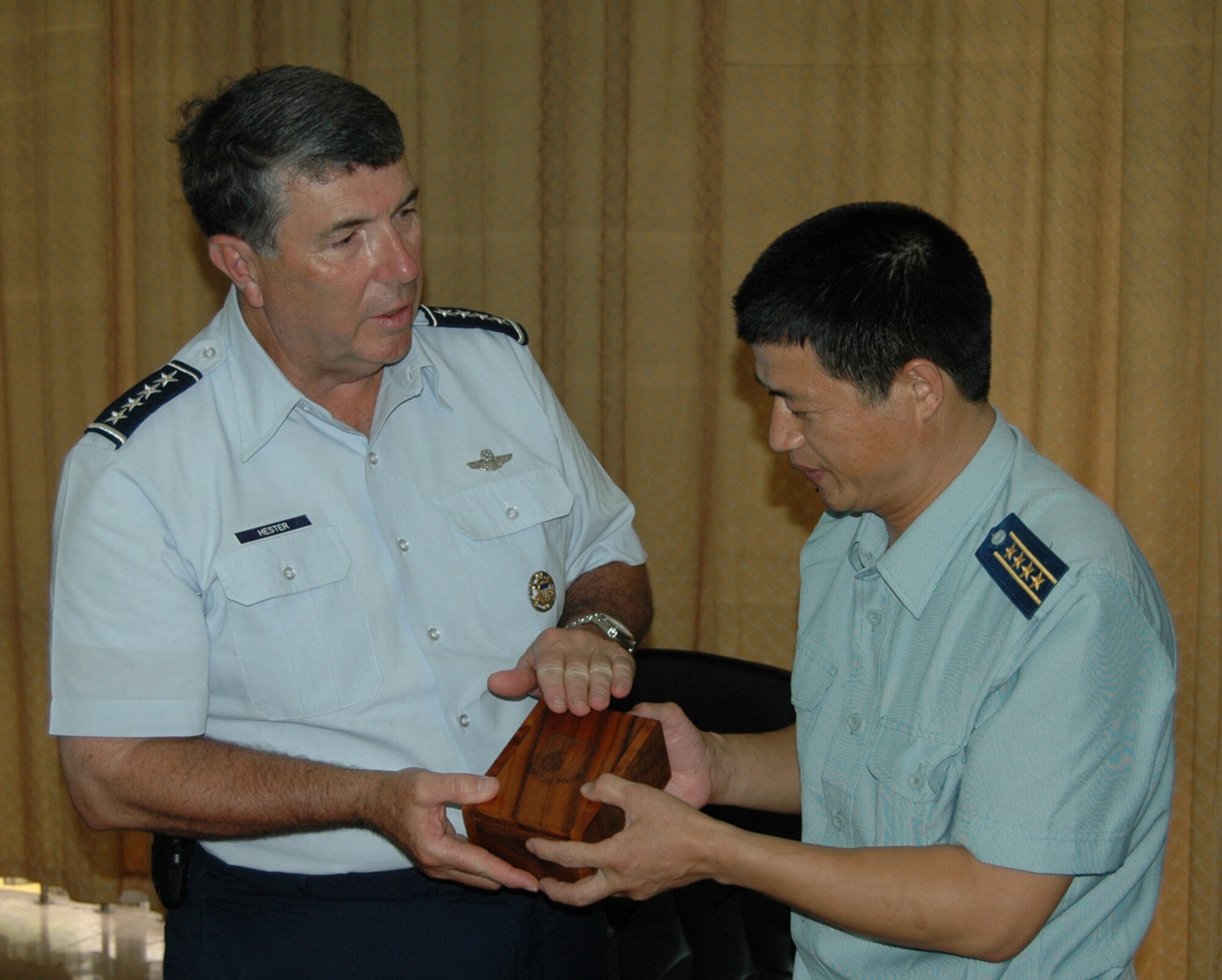 JIANQIAO AIR BASE, China—Gen. Paul V. Hester, commander of Pacific Air Forces, explains the symbolism of Pacific Air Forces on an engraved koa wood box as he presents it to Senior Col. He Quanshou, commander of the 28th Air Division here, People’s Liberation Army Air Force.  (U.S. Air Force photo by Maj. Ray Truong)

