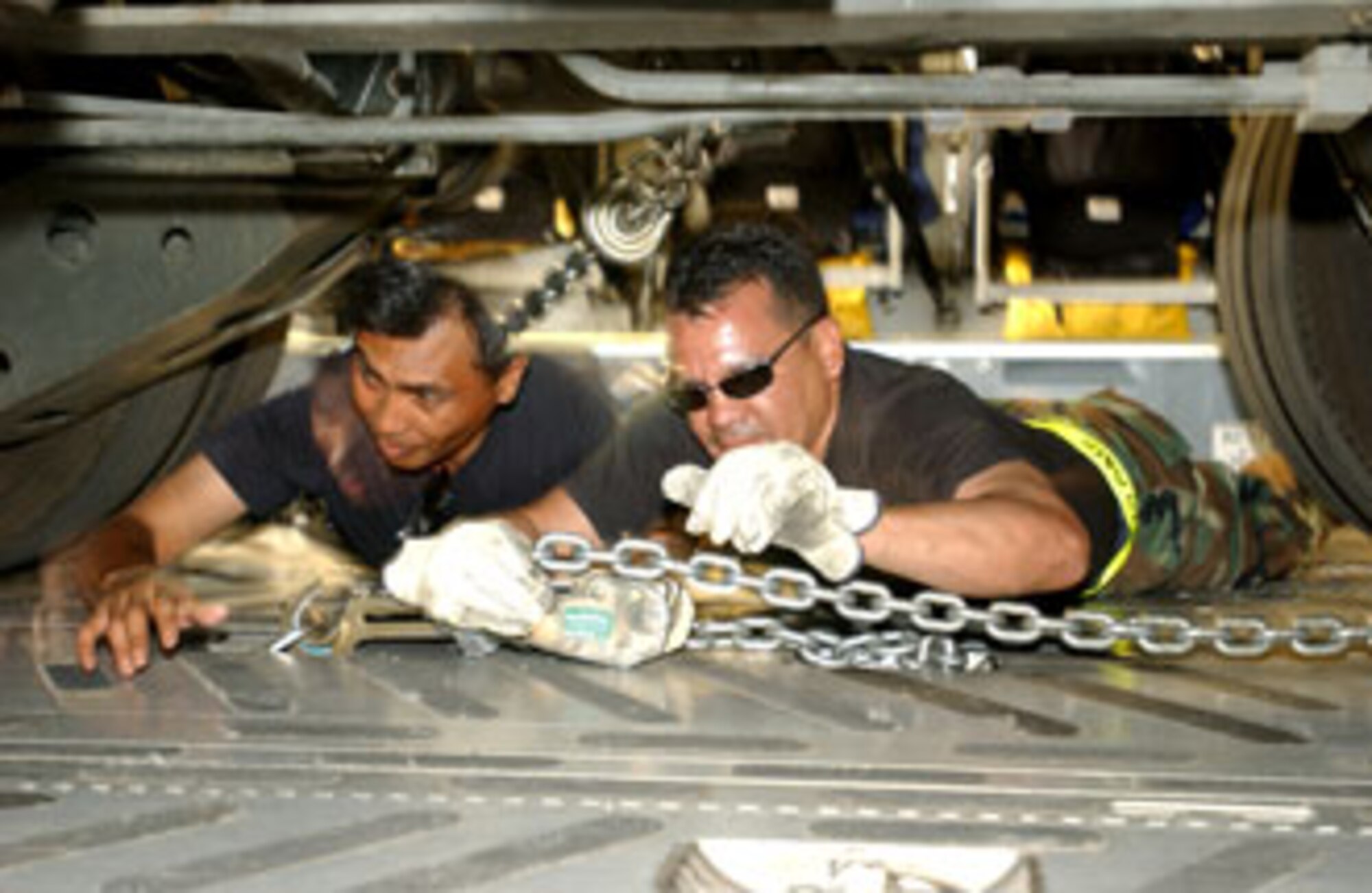 Senior Airman Frederick Eleazar and Senior Airman Kyle Orian, 50th Aerial Port Squadron, tighten down chains to secure a 60k Tunner on a  C-17 Globemaster III at March during Patriot Hook.
U.S. Air Force photo by Senior Airman Sarah N. Sutliff