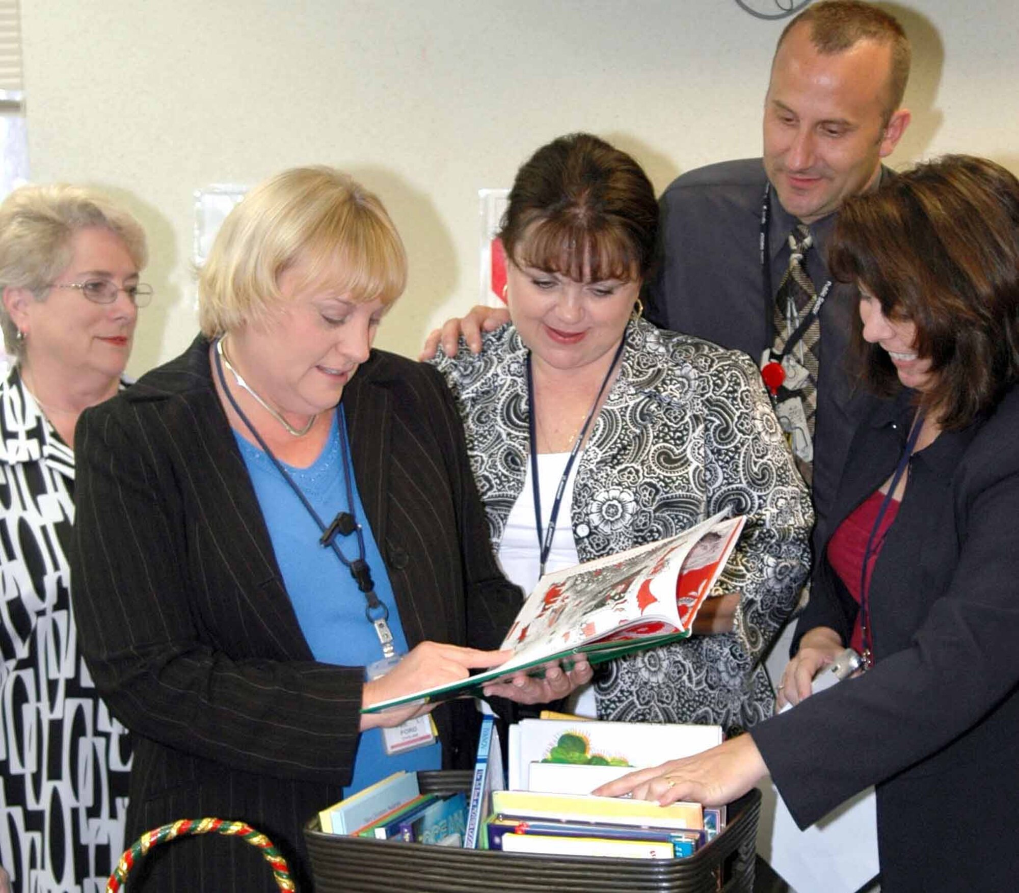From left, Elane Peek, Oklahoma City Air Logistics Center Direcotr of Staff Protocol; Patti Ford, Director of Staff; Rhonda Lugo, DSP; William Calvo, Commanders Action Group; and Lisa Shimkus, Director of Staff Executive Service, gather around a basket of children's books that were collected for the Christmas in July party for the Family Support Center's new "Ready and Reading" program. (Air Force photo by Kathy Paine)