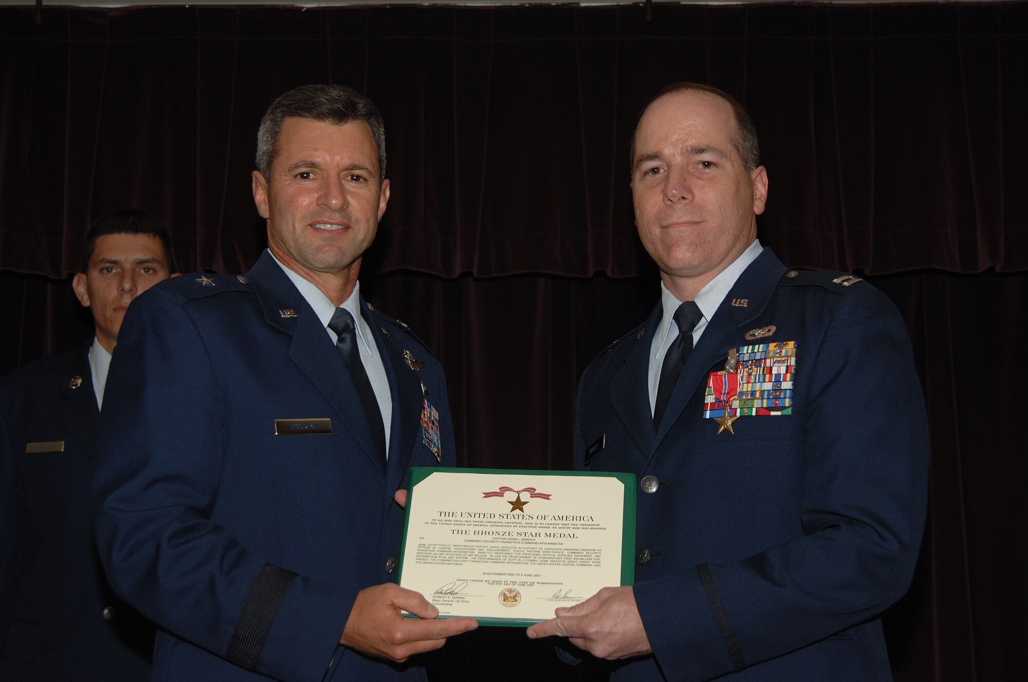 WHITEMAN AIR FORCE BASE, Mo. – Brig. Gen. Greg Biscone, 509th Bomb Wing commander, presents Capt. Adam Minnich, 509th Logistics Readiness Squadron, with a Bronze Star Medal July 20 at the Mission’s End. Captain Minnich was awarded the medal for his exceptional service during Operation Enduring Freedom. (U.S. Air Force photo/Senior Airman Lauren Padden)