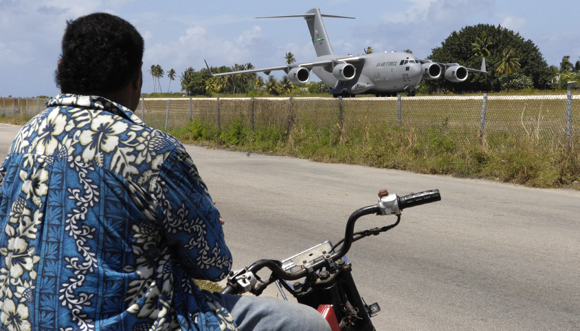REPUBLIC OF NAURU – A local man watches a C-17 Globemaster III from McChord Air Force Base, Wash. land here July 27. The aircraft, piloted by a crew from the 728th Airlift Squadron, picked up a 12-person U.S. Pacific Command team deployed to provide training and assistance to the island's physicians and caregivers. This was the first time a substantial U.S. military presence has been in Nauru since World War II. The island is surrounded by a thick reef, precluding ships from docking, and its airport has a relatively short runway. The C-17's unique ability to land on short runways made this mission possible. (U.S. Air Force photo/Tech. Sgt. Chris Vadnais)