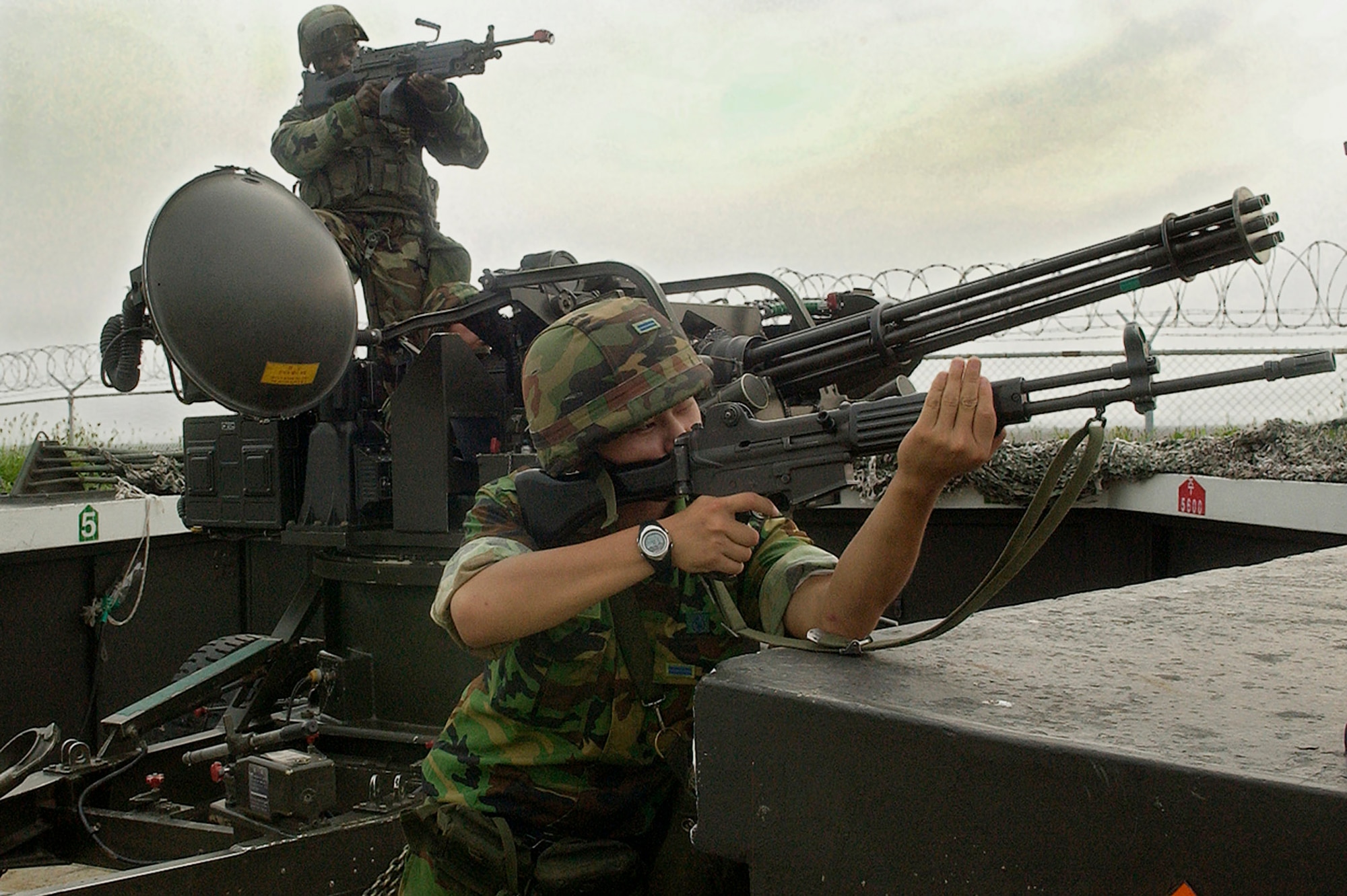 Senior Airman Escott Solomon and Republic of Korea Airman First Class Hyun, Jaehwan take a defensive posture at one of the base's Vulcan cannon batteries during a simulated air attack July 24 at Kunsan Air Base, Republic of Korea. Airman Hyun, 38th Fighter Group anti-aircraft battery, along with Airman Solomon and other Airmen of the 8th Security Forces Squadron, conducted joint training on the anti-aircraft system, enhancing the base's security in the event of hostilities on the peninsula. (U.S. Air Force photo/Senior Airman Giang Nguyen)