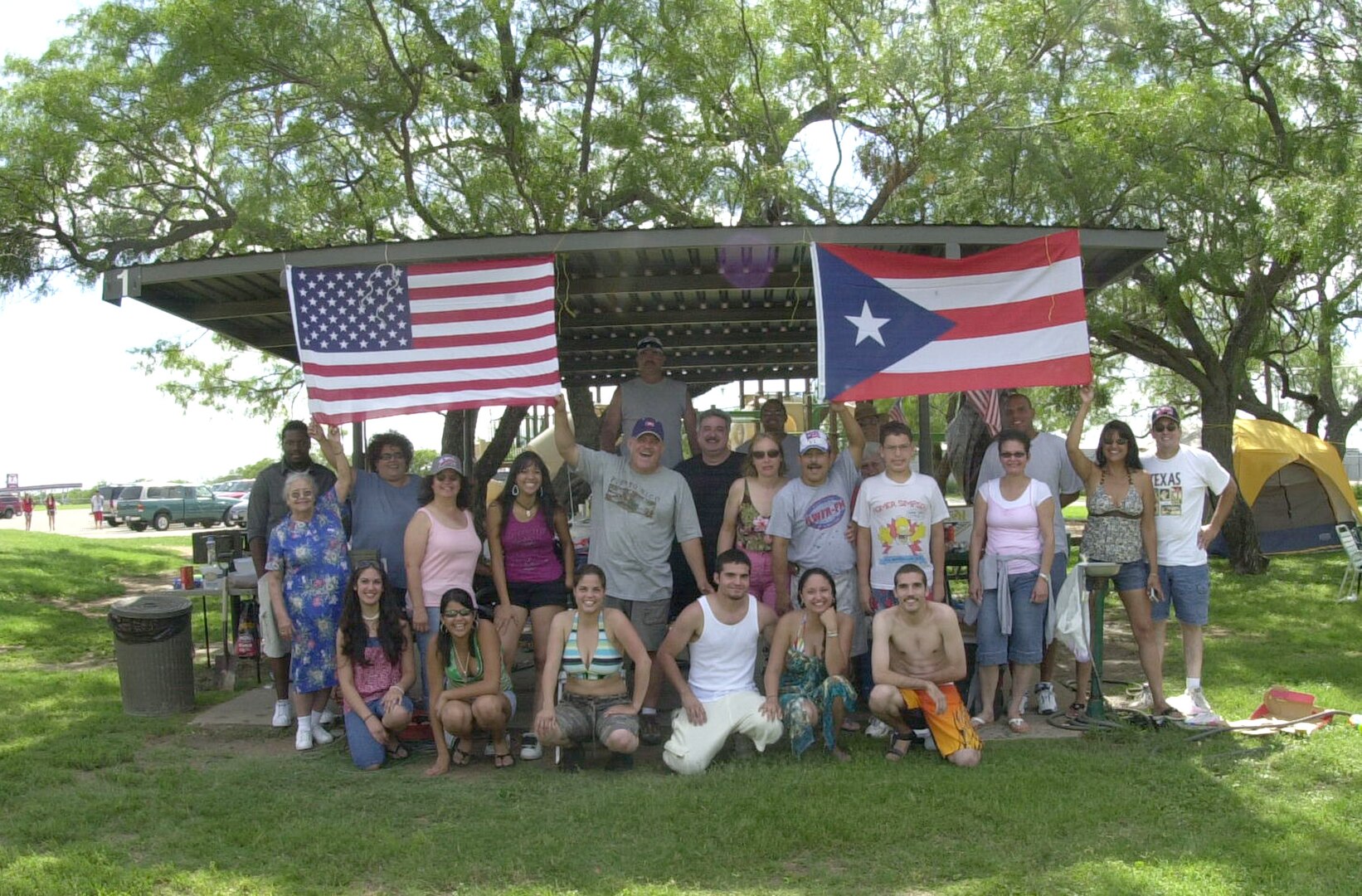 Carlos Santana (located below left hand of Puerto Rican flag), a supply clerk for the Army’s  344th Military Intelligence Battalion, is joined by family and friends as he and his wife Trisha (standing to the left) celebrate the Fourth of July for the fourteenth consecutive time at the Goodfellow Recreational Camp at Lake Nasworthy.  
“It is important to spend time with family and those who are close to you on special days like the Fourth of July,” said Mr. Santana. The Santanas and their guests prepared Puerto Rican-style food to go along with the traditional American barbecue food of burgers and hot dogs.

Dozens of other people spent  their Fourth of July at the camp barbecuing and taking advantage of the amenities. (U.S. Air Force photo by Airman 1st Class Luis Loza Gutierrez)