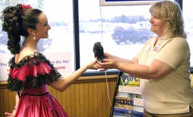 Heather McKain, a performer at Dolly Parton's Dixie Stampede in Branson, Mo., presents a bronze "Stampede of the Buffaloes" statuette as a token of appreciation to Gabriele Church, Tinker Information, Tickets and Travel director. The award extends a special "thank you" to the ITT office for the services they provide to active duty and retired military personnel and their families. (Air Force photo by Becky Pillifant)