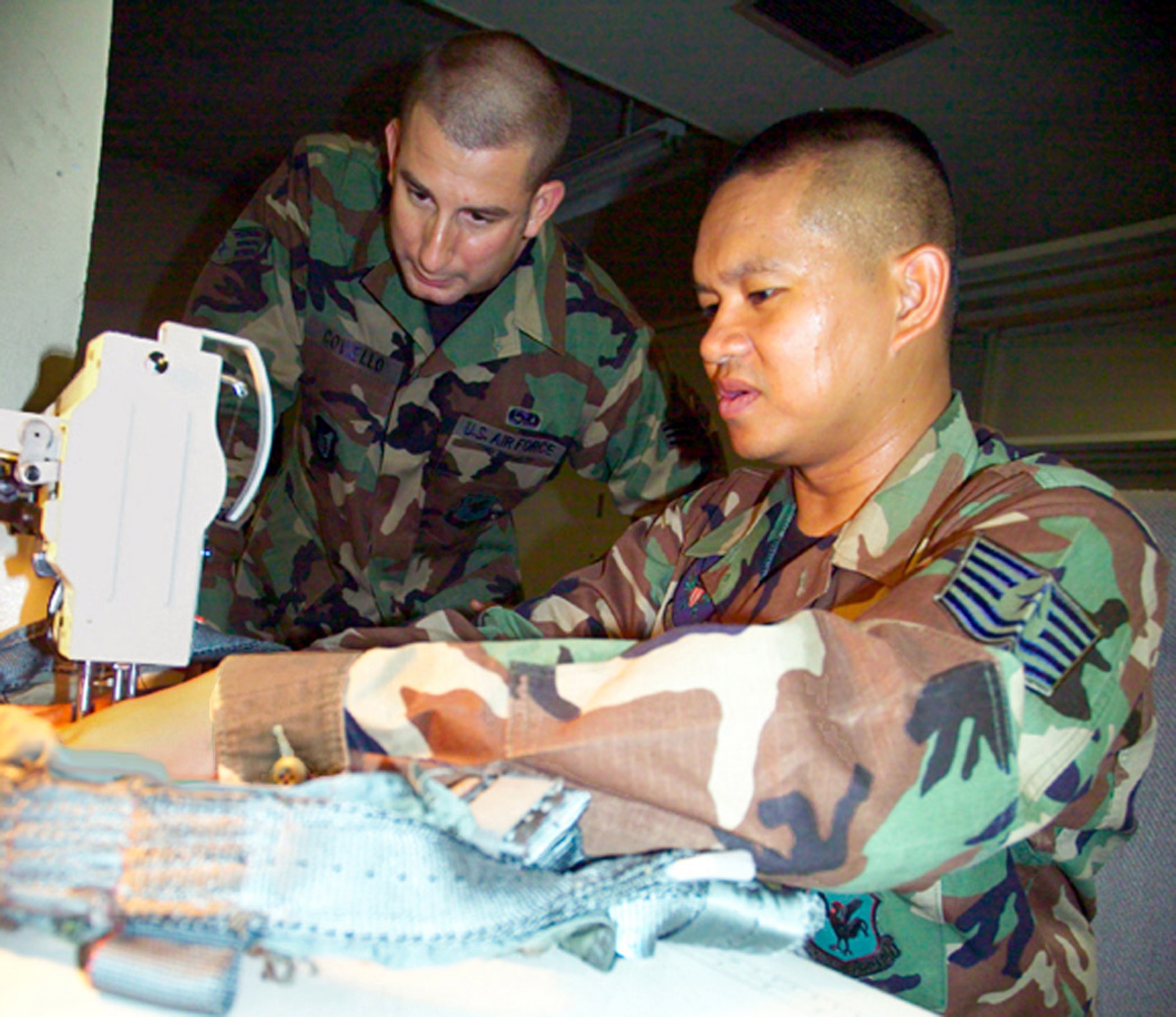 Airman 1st Class Robert Coviello (left) instructs Tech. Sgt. Calvin Warner on sewing techniques for repairing a harness July 12 as part of cross-utilization training being conducted at the 18th Operations Support Squadron at Kadena Air Base, Japan, to merge aircrew life support and survival equipment into a new Air Force specialty code, aircrew flight equipment.  (U.S. Air Force photo/Scott Hallford)