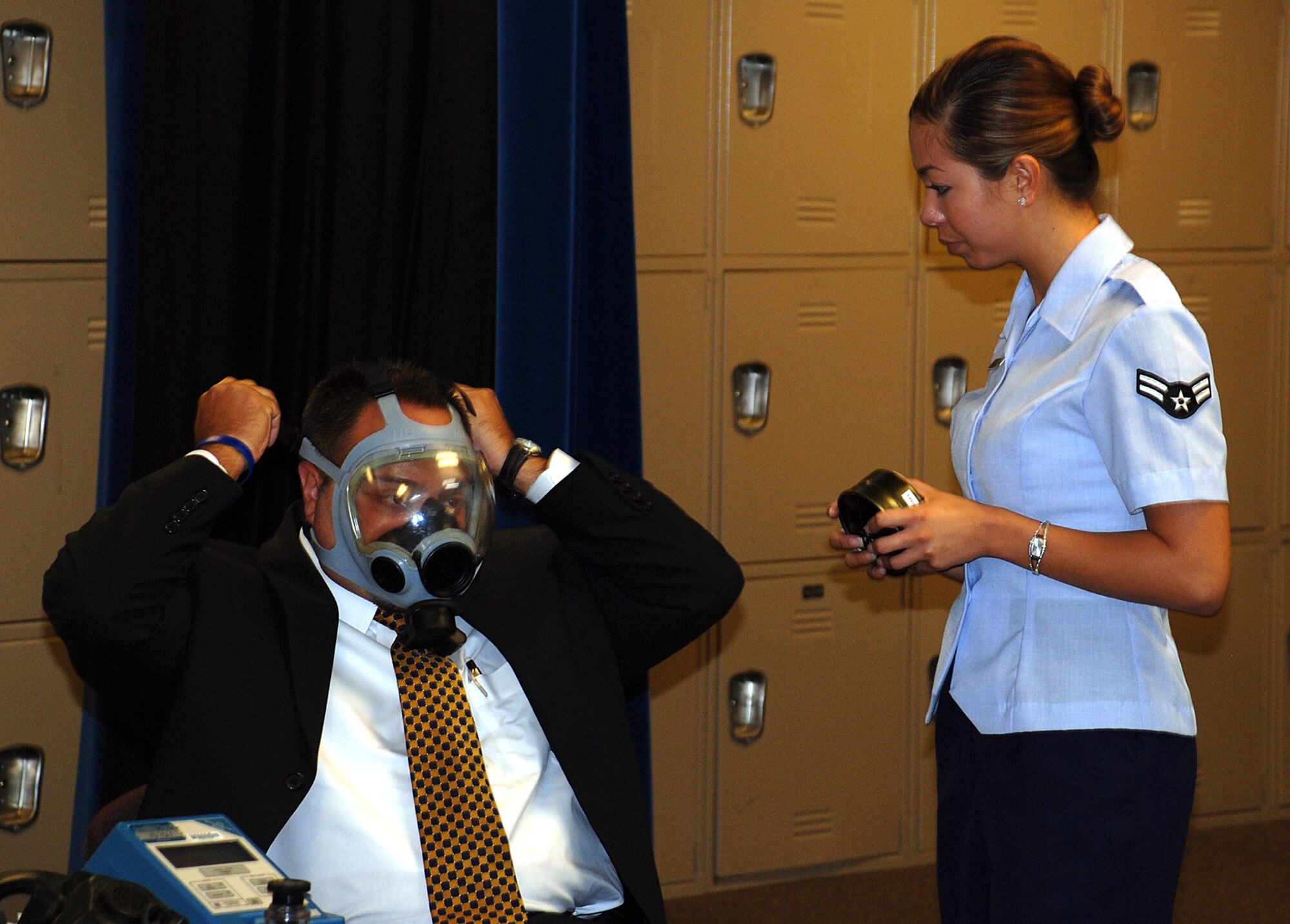 MCCONNELL AIR FORCE BASE, Kan. -- Airman 1st Class Robyn Matthew, 22nd Aeromedical-Dental Squadron, helps Claudio Ferraro, vice president of strategic planning and marketing at Via Christi Hospital and 22nd Medical Group honorary commander put on a gas mask July 31. Honorary commanders visited McConnell to gain a better understanding of how the medical group operates and provides service to approximately 400-500 active duty, reserve and retired military members and their families on a daily basis. (photo by Airman 1st Class Jessica Lockoski)