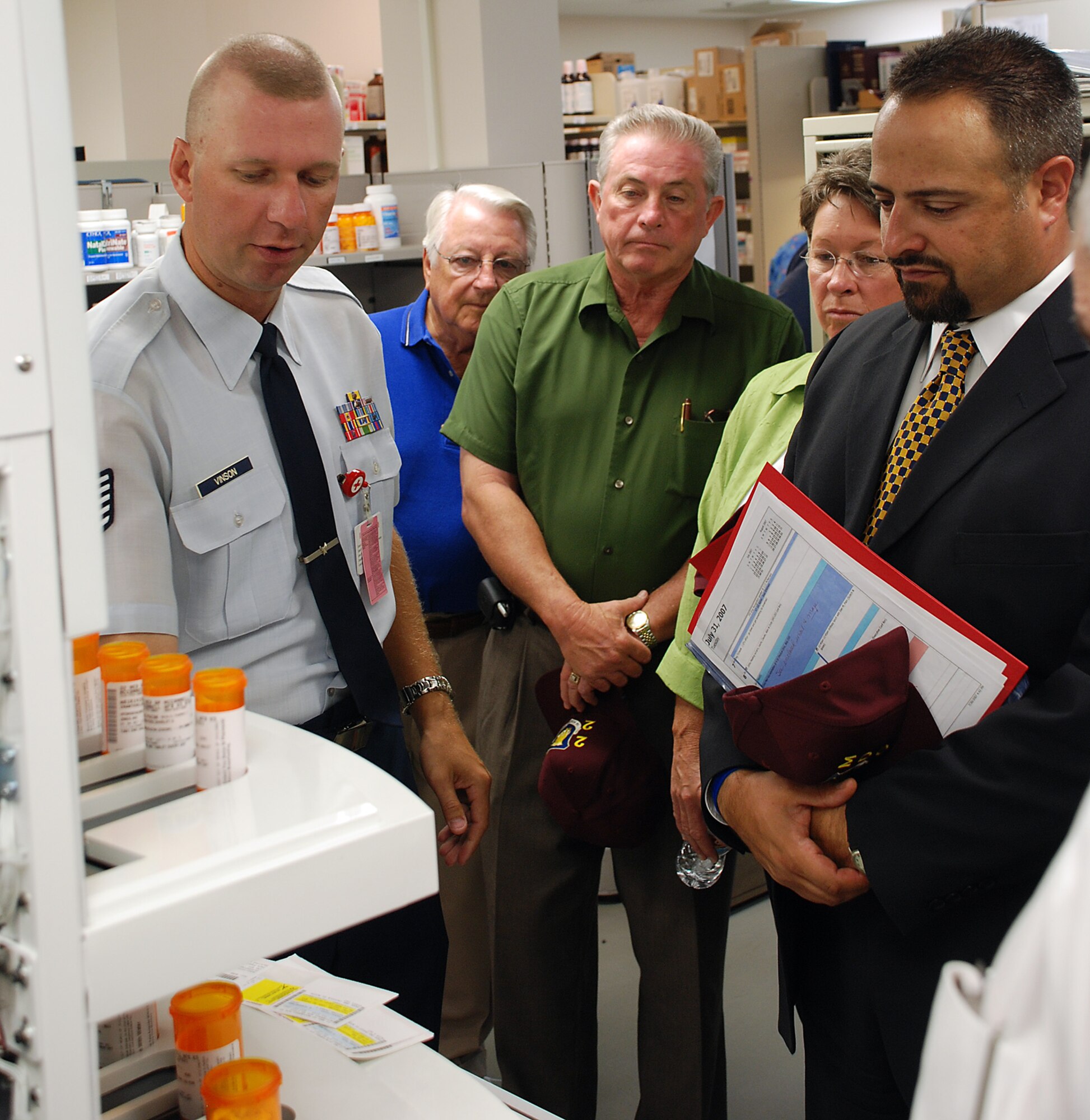 MCCONNELL AIR FORCE BASE, Kan. -- Tech. Sgt. Johnny Vinson, 22nd Medical Support Squadron, explains to honorary commanders, how PharmAssist, the new automated pharmacy prescription refilling machine, improves the pharmacy inventory management. The group of honorary commanders where given a tour of the medical group facilities July 31. The honorary commanders learned how the robotic re-filler brings cost savings and reduced the workload of clinic staff member enabling the clinic to focus more on patient care. (photo by Airman 1st Class Jessica Lockoski)