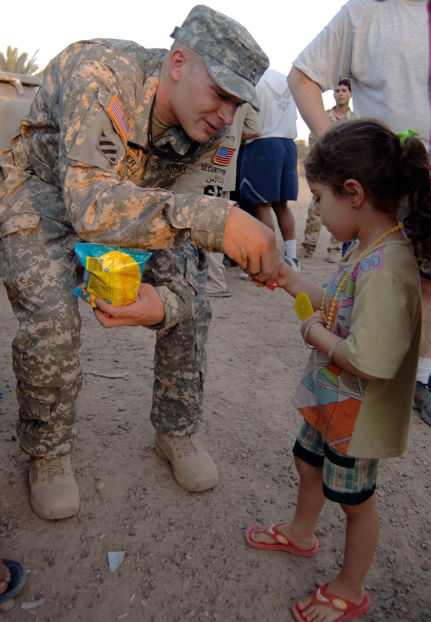 Army Pfc. Jeremy Breuckner offers candy to an Iraqi child at the Victory Base Complex in Iraq July 29. This was part of an Air Force effort to provided humanitarian aide to children of Iraqi soldiers. Other items passed out were school supplies, clothing and soccer balls. Private Breuckner is a 447th Expeditionary Security Forces Squadron patrolman. (U.S. Air Force photo/Tech. Sgt. Russell Wicke)