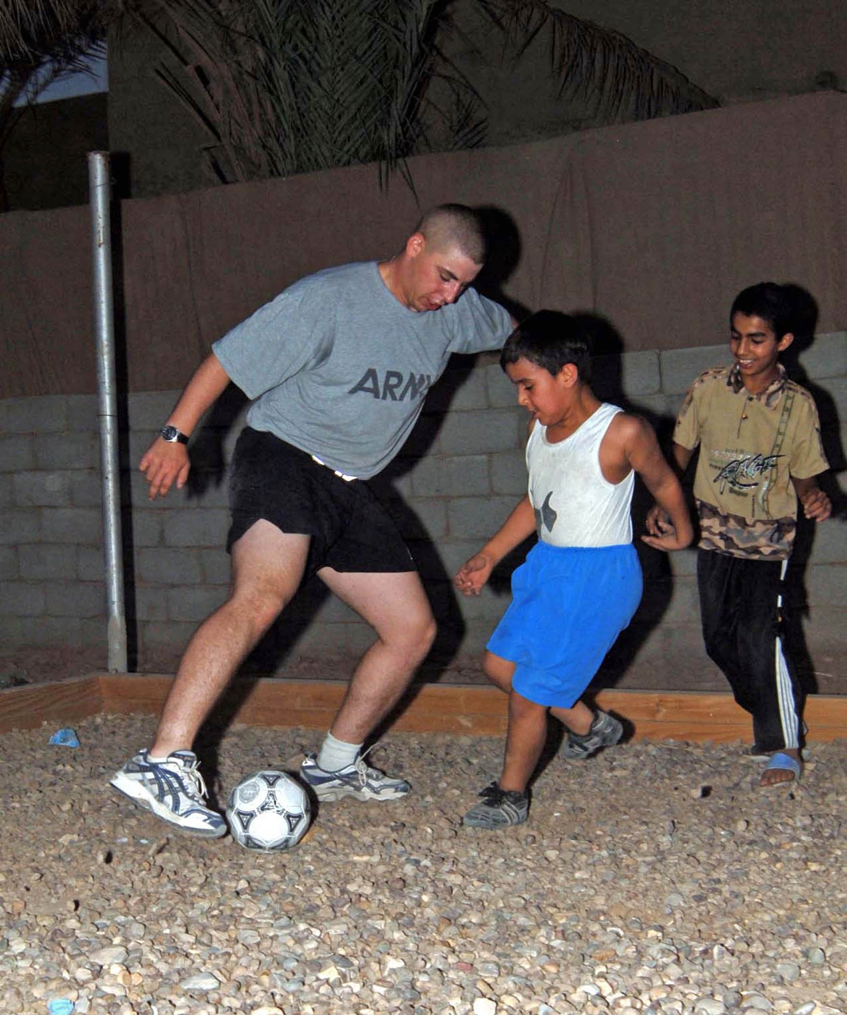 Army Spc. Kyle Hanlan plays an impromptu game of soccer with Iraqi children at the Victory Base Complex in Iraq. The visit was part of an Air Force effort to provide humanitarian aide to children of Iraqi soldiers. Specialiast Hanlan is a 447th Expeditionary Security Forces Squadron patrolman. (U.S. Air Force photo/Tech. Sgt. Russell Wicke)