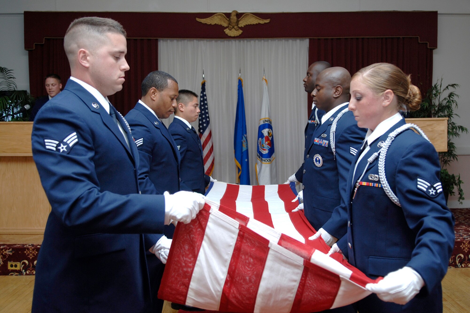 From left, left line: Senior Airmen Brett J. Reed, Aaron E. Minor, Prudencio Olmos, and From right, right line: Senior Airmen Michelle K. Urso, Thomas J. Credit and Evans O. Opoku participate in a flag folding ceremony conducted during the Airman Leadership School graduation held July 27 in the Minuteman Club. Eleven servicemembers graduated during the ceremony. The next ALS graduation is scheduled Oct. 5. The five-week ALS course is the first step of Professional Military Education for all enlisted Airmen. The class is required to be taken in residence before servicemembers are promoted to the rank of staff sergeant. (U.S. Air Force photo by Jan Abate). 

