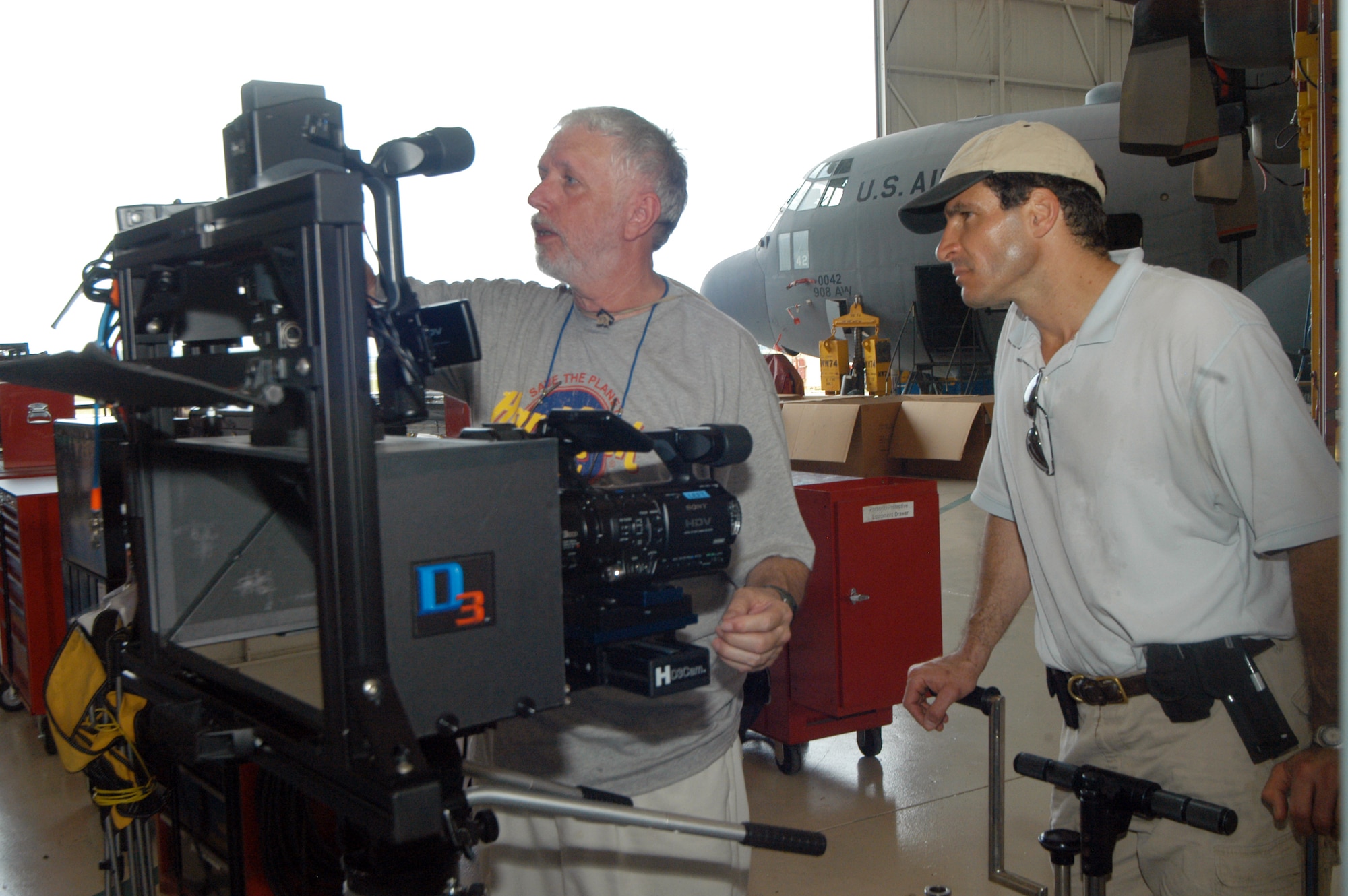 Daniel Symmes, co-director and cameraman, and Paul Huth, key grip, place camera equipment for scenes in a C-130 hangar for a 3-D safety film at Robins this week. U. S. Air Force photo by Sue Sapp  