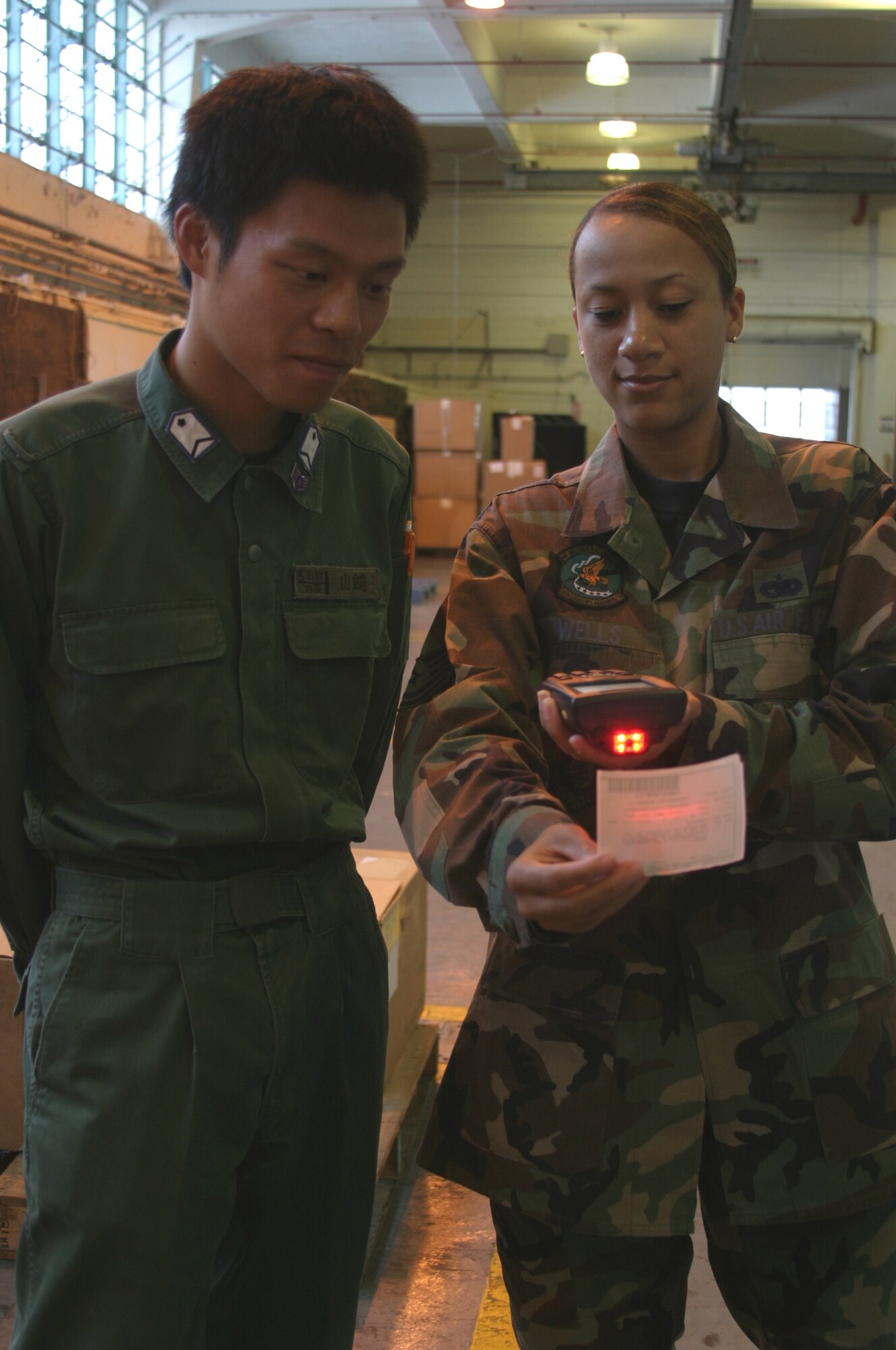 Technical Sgt. Lisa Wells (right), 18th Logistics Readiness Squadron material management specialist, uses a bar code scanner to show Japan Air Self Defense Force Staff Sgt. Tsugumasa Yamazaki how items are received and stocked in her squadron July 25. Seven JASDF military members recently took part in an exchange program where each member was paired with a Kadena sponsor, allowing them to spend time together and learn how their respective country's military does business.
(U.S. Air Force/Senior Airman Nestor Cruz)