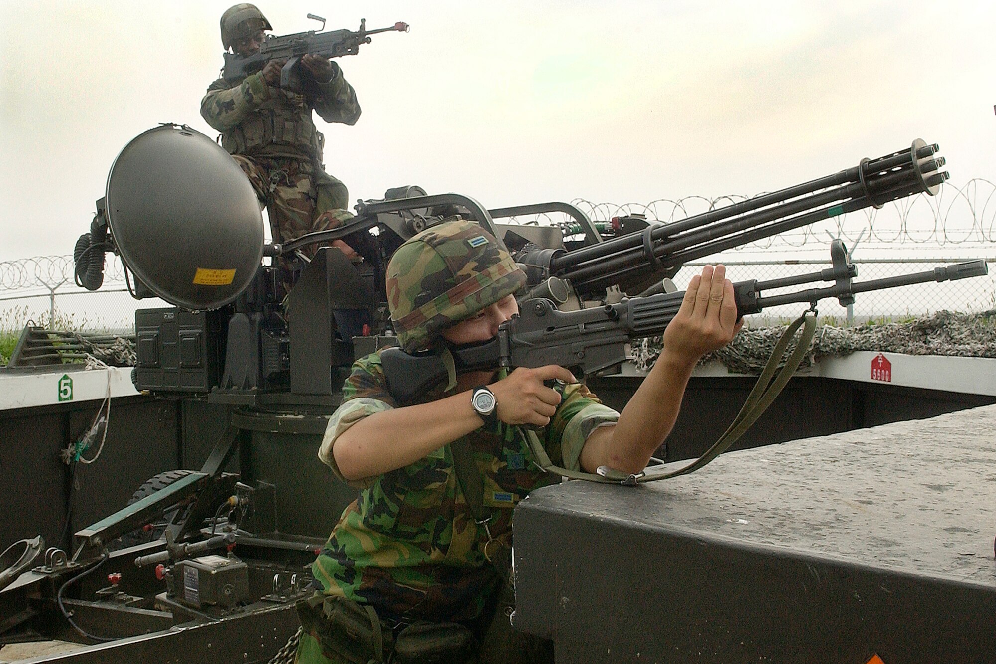 KUNSAN AIR BASE, Republic of Korea -- Senior Airman Escott Solomon and ROK Airman First Class Hyun, Jaehwan take a defensive posture at one of the base's Vulcan cannon batteries during a simulated air attack July 24. Airman Hyun, 38th Fighter Group anti-aircraft battery here, together with Airman Solomon and other Airmen of the 8th Security Forces Squadron conducted joint training on the anti-aircraft system, enhancing the base's security in the event of hostilities on the peninsula. (U.S. Air Force photo/Senior Airman Giang Nguyen)