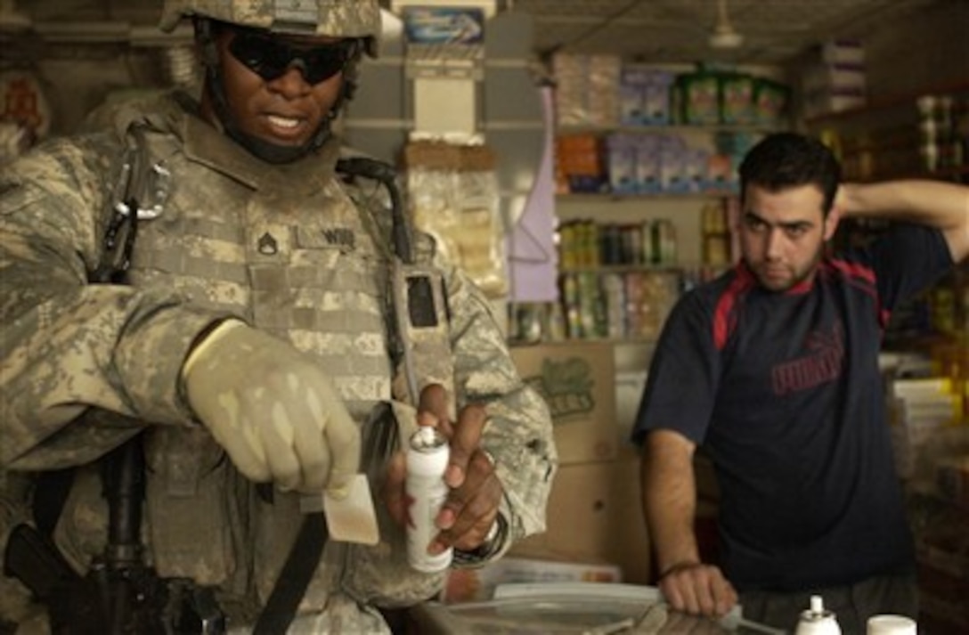 U.S. Army Staff Sgt. Frank Woode looks for a positive identification of explosives residue on an Iraqi man's hands at Hateen Market during a patrol in the Mansour district of Baghdad, Iraq, on July 31, 2007.  Woode is attached to Alpha Battery, 2nd Battalion, 32nd Field Artillery Regiment, 4th Brigade Combat Team, 1st Infantry Division.  