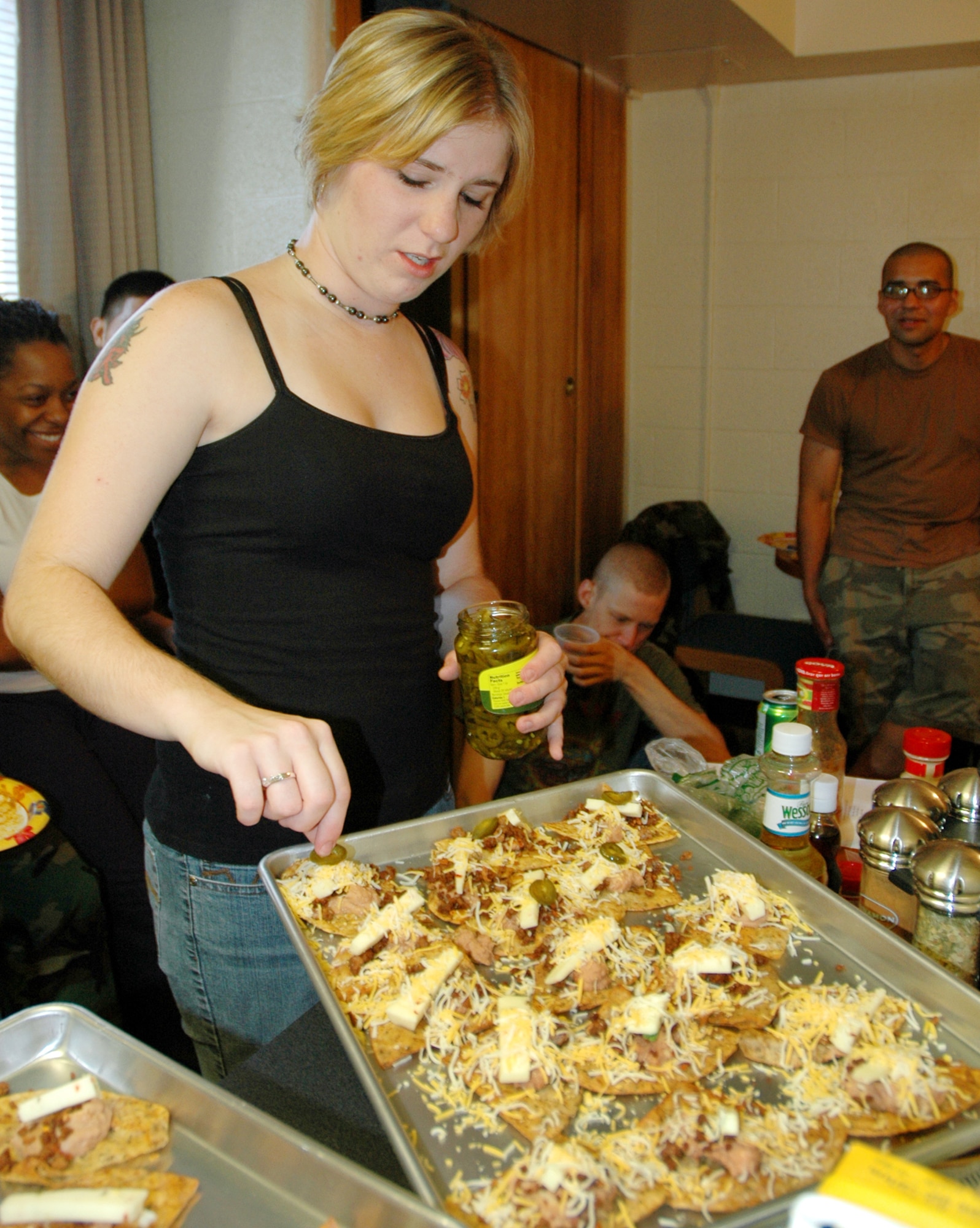 Airman 1st Class Marleah Miller, 844th Communications Group, adds the finishing touch to the “macho nachos,” one of the several Mexican-American dishes prepared July 31 during a dormitory cooking class at Blanchard Barracks. (U.S. Air Force photo by Airman 1st Class R. Michael Longoria)