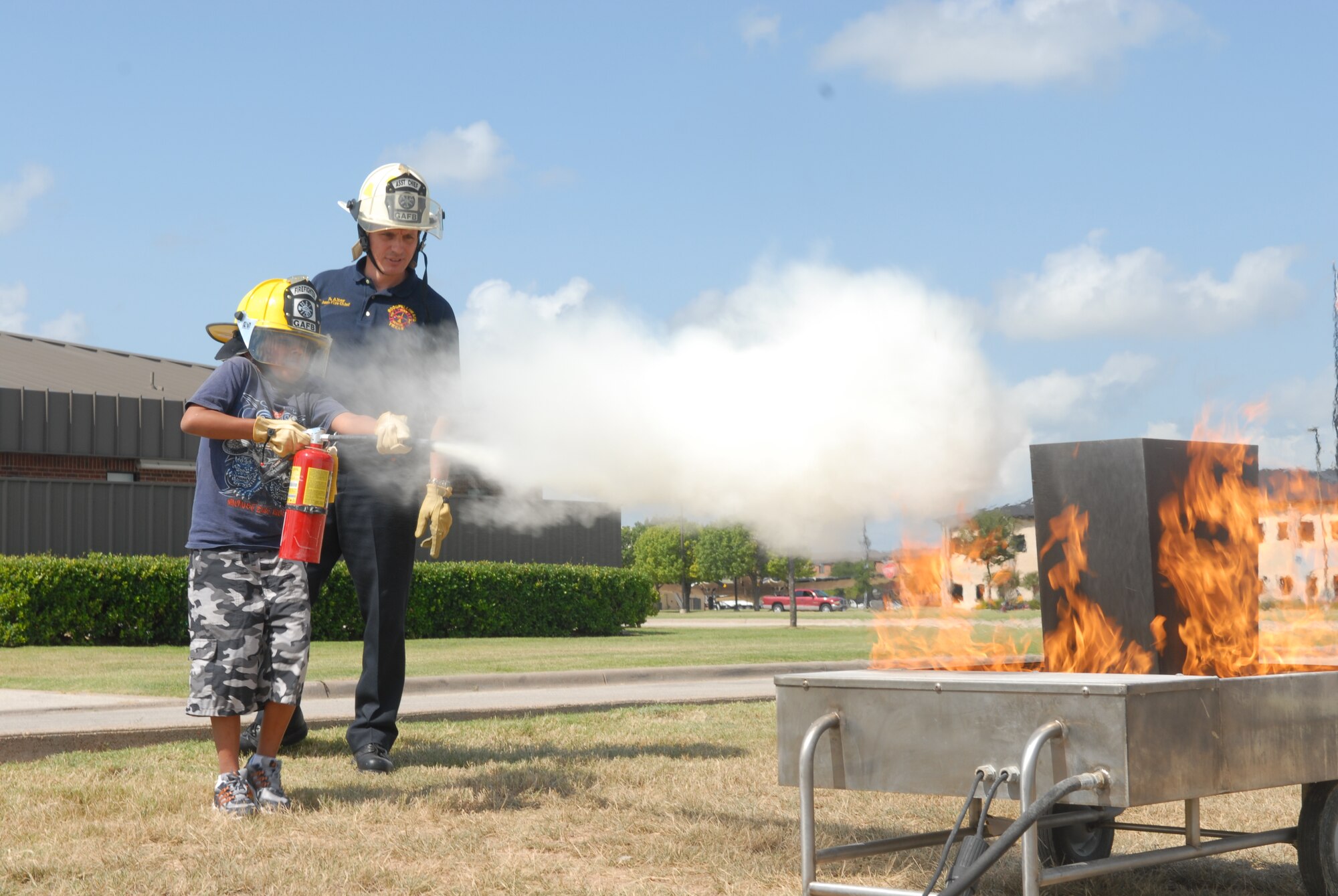 Eleven-year-old James Rivera uses a fire extinguisher under the supervision of Assistant Fire Chief Richard Alter. (U.S. Air Force photo by Airman 1st Class Kamaile Chan)