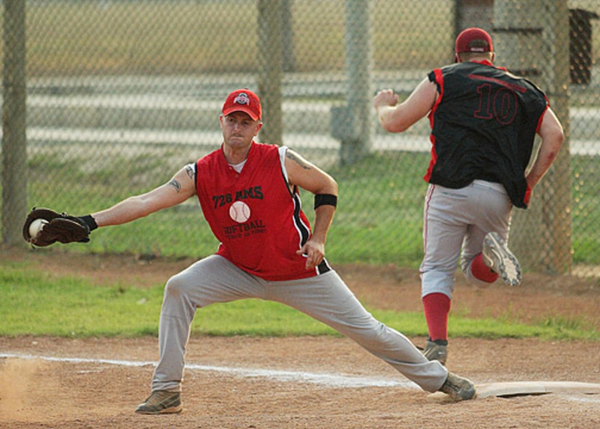 AMS' first baseman Thomas Wesserman stretches to take the throw as AMMO's Corey Genzel crosses the bag during the first game of the championship.  AMMO went on to win the second game 11-10 over the 728th Air Mobility Squadron. (U. S. Air Force photo by Ismael Gomez)