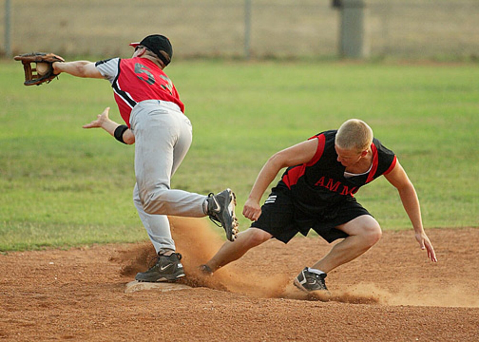 AMS' second baseman Anthony Butts stretches to take the throw as AMMO's Donavan Leap slides into the bag during the first game of the championship.  AMMO went on to win the second game 11-10 over the 728th Air Mobility Squadron. (U. S. Air Force photo by Ismael Gomez)