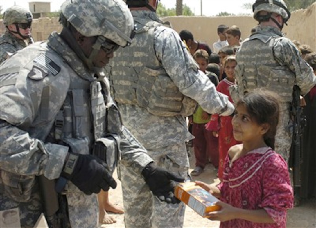 Command Sgt. Maj. Marvin L. Hill, Multi-National Force-Iraq command sergeant major, hands cookies to an Iraqi girl in the village of Al Jumia, Iraq, July 2, 2007.
