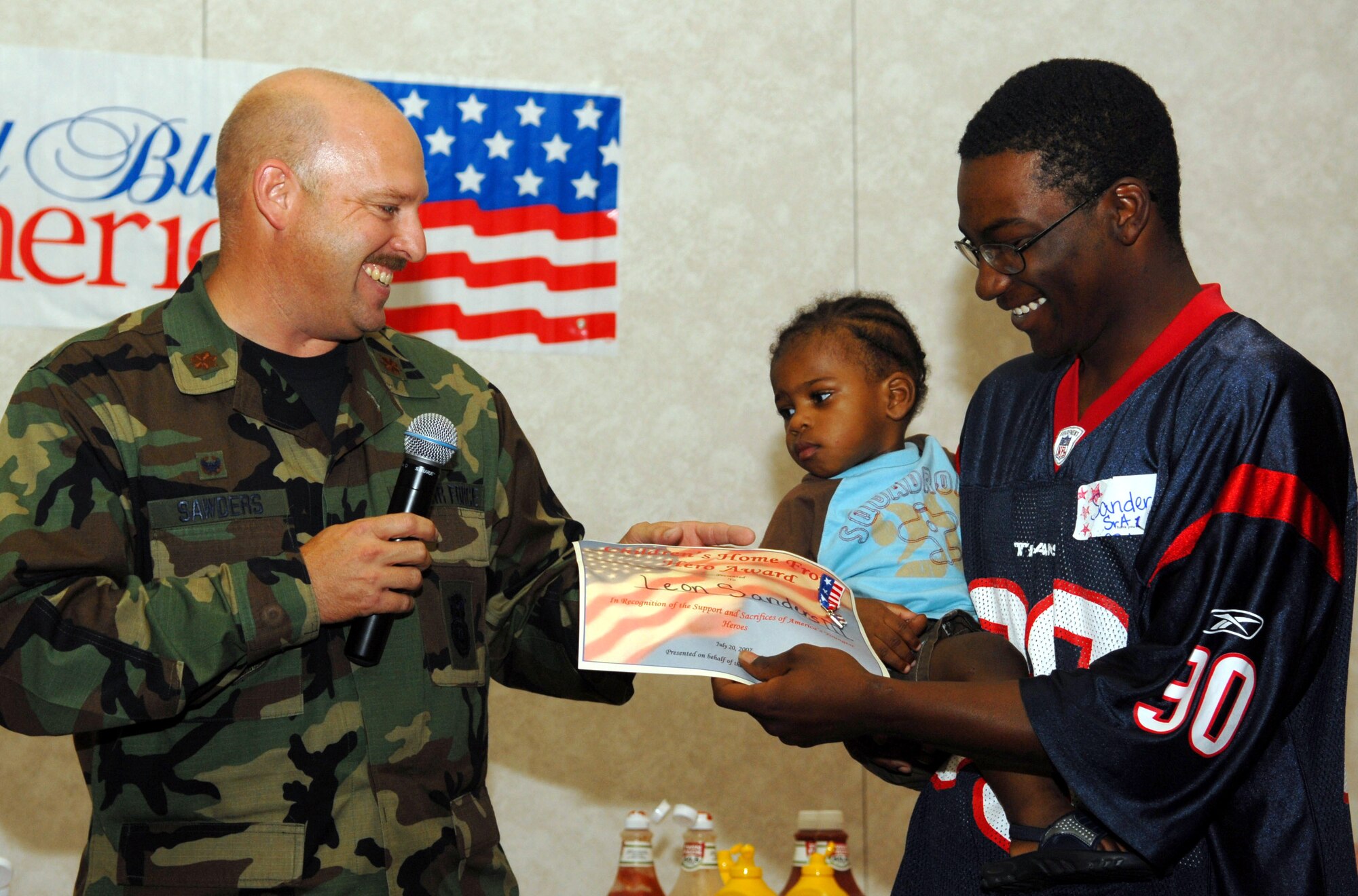 Major Hunter Sawders, 17th Security Forces Squadron commander, presents 15-month-old Leon Sanders III, with a certificate of appreciation during the pre-deployment picnic. (U.S. Air Force photo by Airman 1st Class Kamaile Chan)