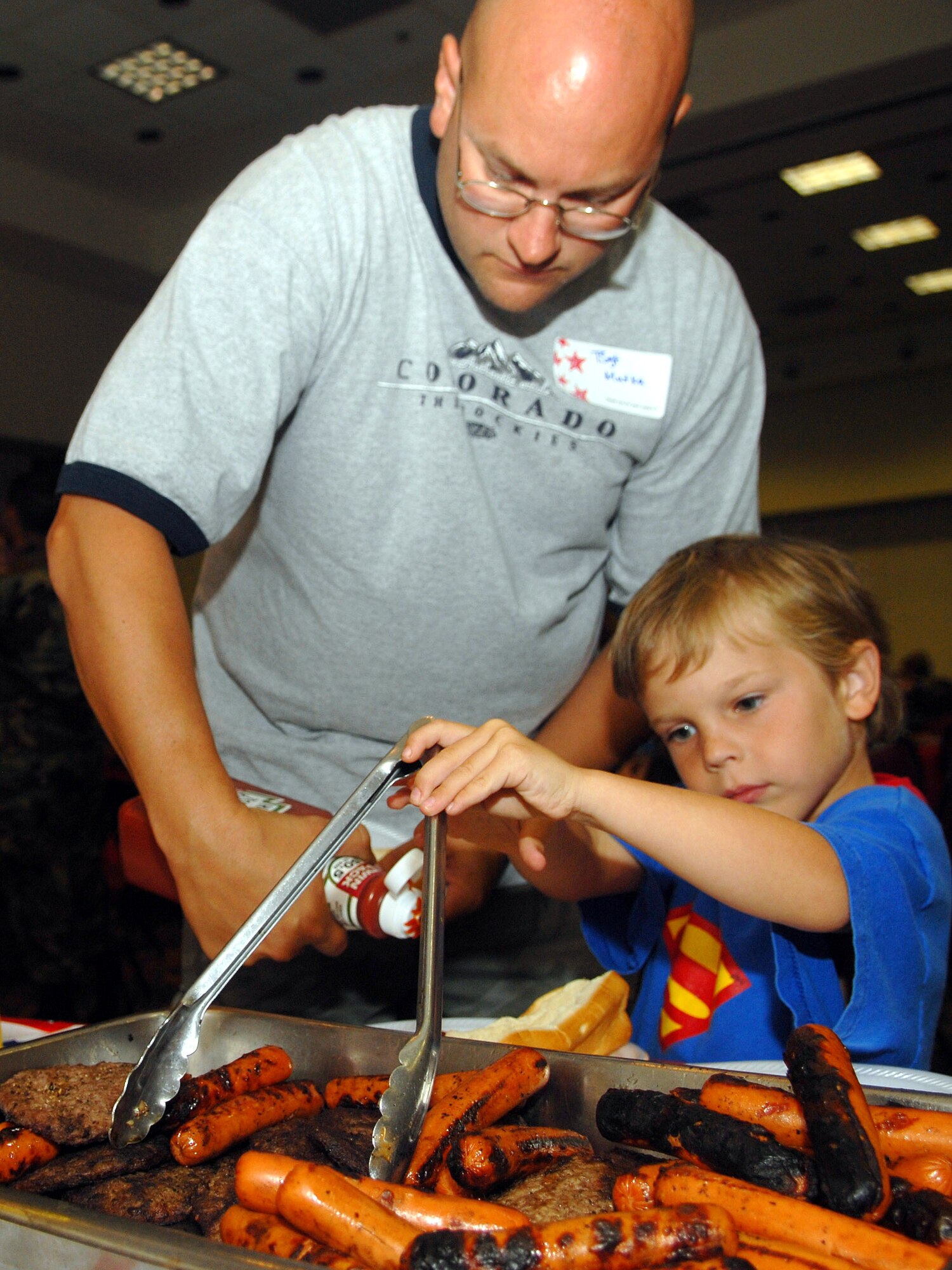 Tech. Sgt. Steven Mutka, a deployee from the 17th Security Forces Squadron, and son Andrew Mutka serve themselves during the pre-deployment picnic at the Goodfellow Event Center July 20. (U.S. Air Force photo by Airman 1st Class Kamaile Chan)