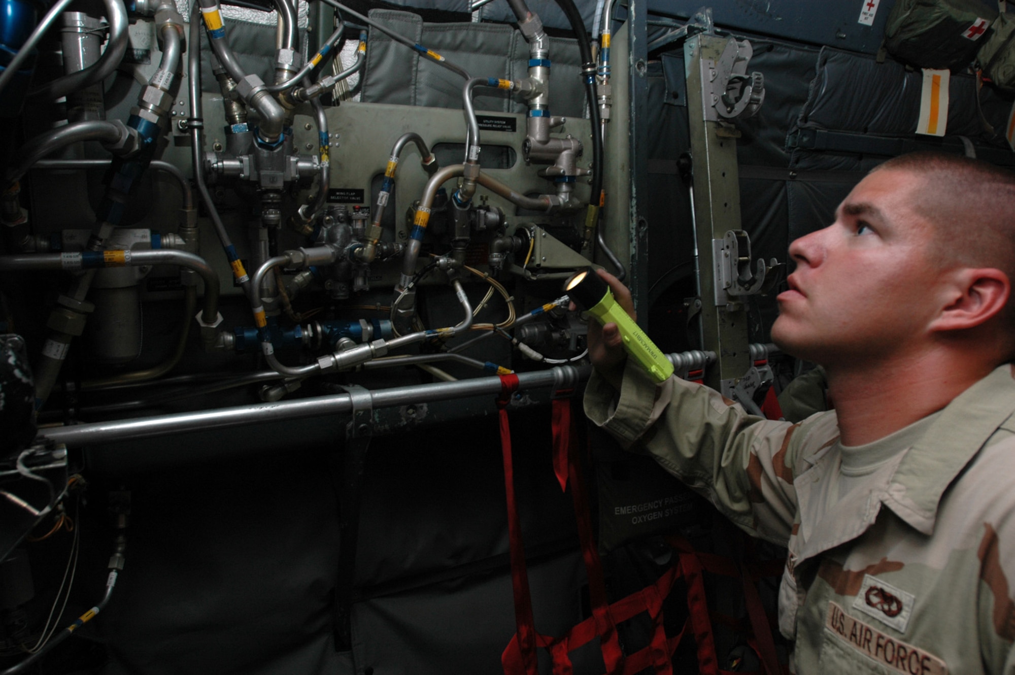 Senior Airman Joe Smigielski, 746th Aircraft Maintenance Unit with the 379th Expeditionary Aircraft Maintenance Squadron, inspects hydraulics lines inside a C-130. Airman Smigielski is a C-130 flying crew chief and is deployed here from Dyess Air Force Base, Texas.  (U.S. Air Force photo by Senior Airman Clark Staehle)