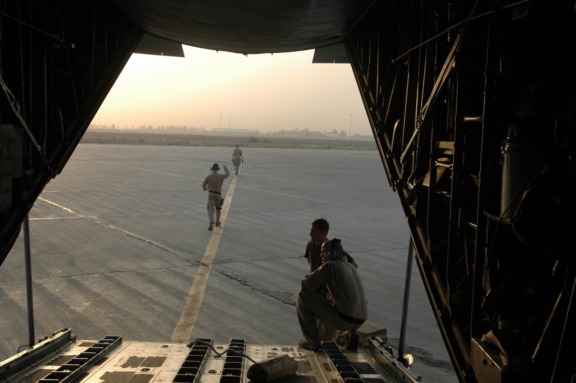 Airman 1st Class Zachary Kelhi and Staff Sgt. Tommy Greeness prepare to receive information from Airmen as the sun rises over Baghdad International Airport. This was the last stop on their mission prior to flying back to the 379th Air Expeditionary Wing.  (U.S. Air Force photo by Capt. Teresa Sullivan)