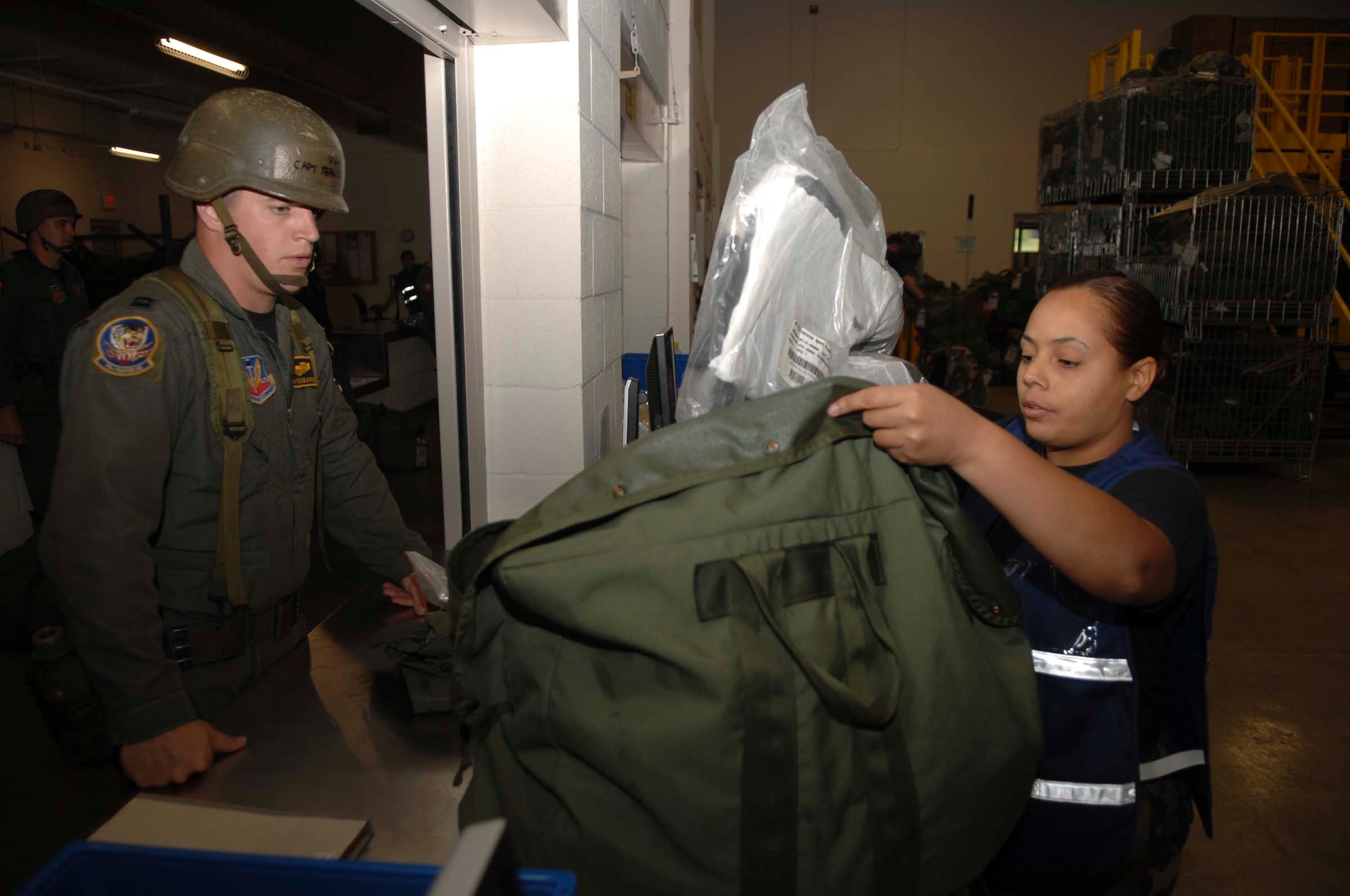 SHAW AIR FORCE BASE, S.C. -- Airman 1st Class Ondina Flores, 20th Communications Squadron base information transfer center custodian, inspects a mobility bag ensuring the proper chemical warfare gear is accounted for before issuing it to Capt. Sean Renbarger, 79th Fighter Squadron F-16CJ pilot, at the Chandler Deployment Processing Center during an Operational Readiness Inspection Aug. 6. The ORI validates the expeditionary skill set of the 20th FW. (U.S. Air Force photo/Staff Sgt. Nathan Bevier)