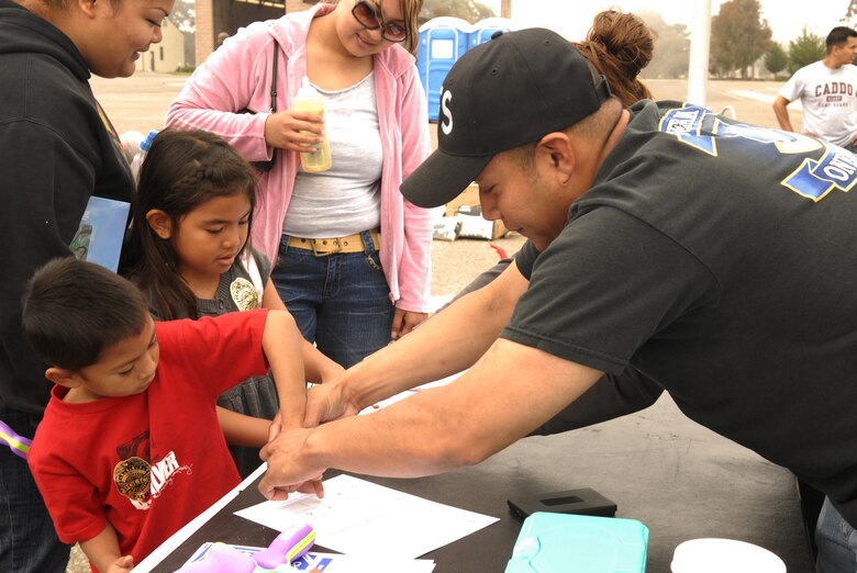 VANDENBERG AIR FORCE BASE, Calif. -- Staff Sgt. Edwin Ventura fingerprints Xanaquin Concepcion, 5, during the 30th Space Wing flea market event on Aug. 4.  The fingerprinting was a free service courtesy of the 30th Security Forces Squadron to assist parents build a child identification kit for their child. The flea market event, sponsored every year by the 30th Services Division to encourage community involvement, allows the community come together and sell items  (U.S. Air Force photo/Airman 1st Class Adam Guy)