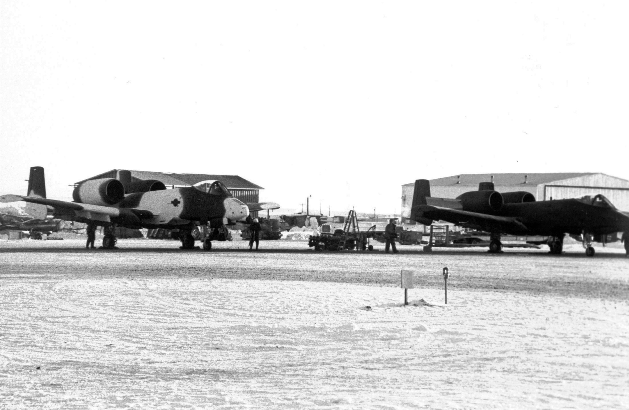 EIELSON AIR FORCE BASE, Alaska--An A-10 with an arctic paint scheme sits next to an A-10 with a regular all gray or green paint scheme sit on the flightline March 1982. That year, an A-10 was repainted in an arctic camouflage scheme as an experiment for an upcoming exercise titled OPERATION Cool Snow Hog. (File photo)